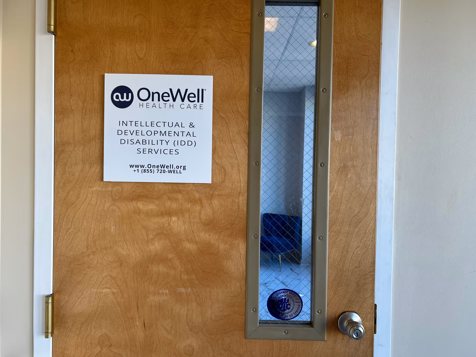Wooden door with a glass window panel and OneWell Health Care sign.