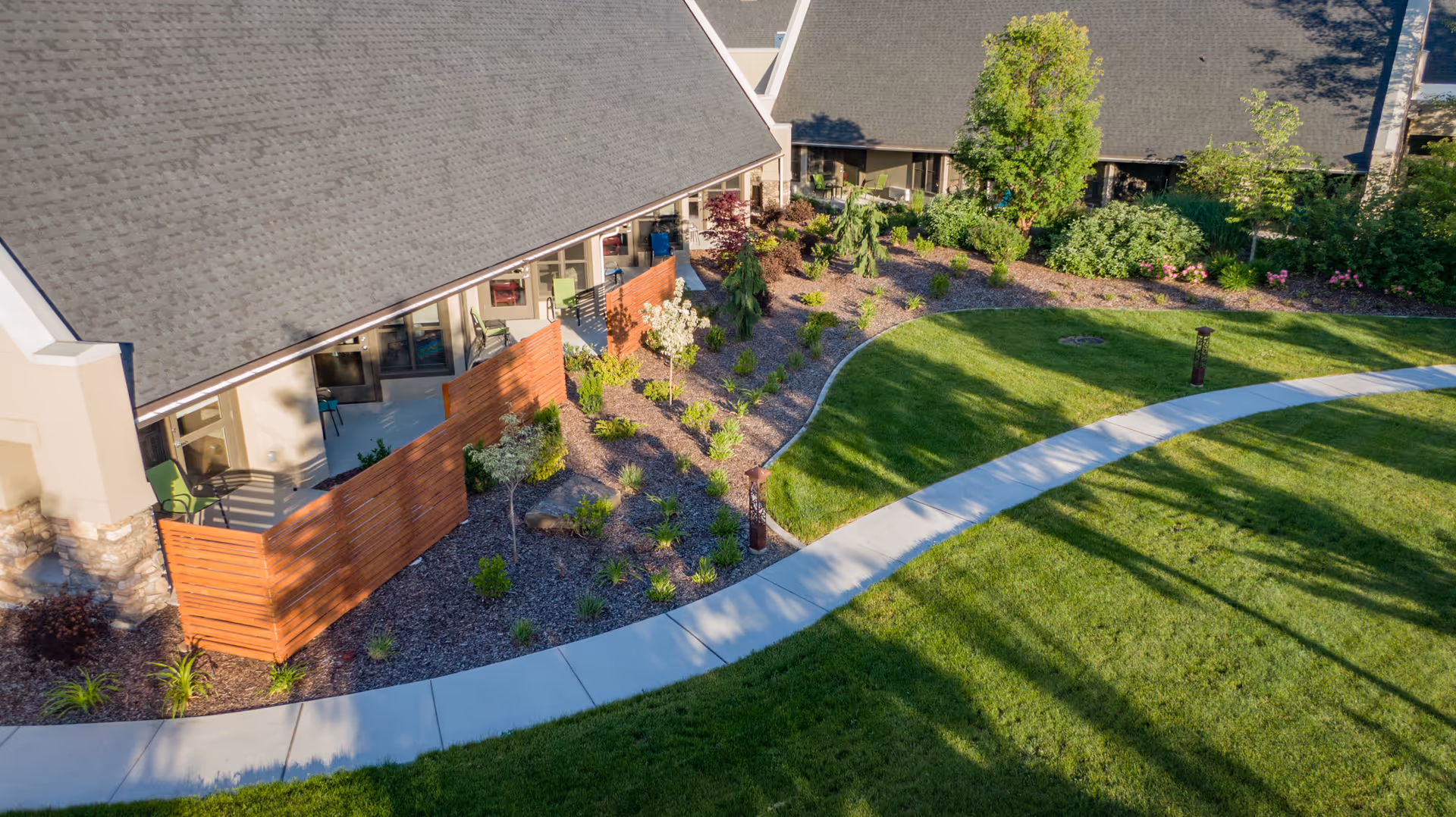 Aerial view of a curved walkway and landscaped courtyard beside a senior living building.