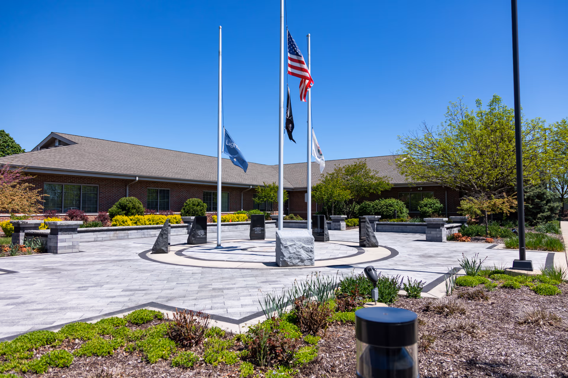 Hospice facility exterior with a circular flag plaza and manicured landscaping.