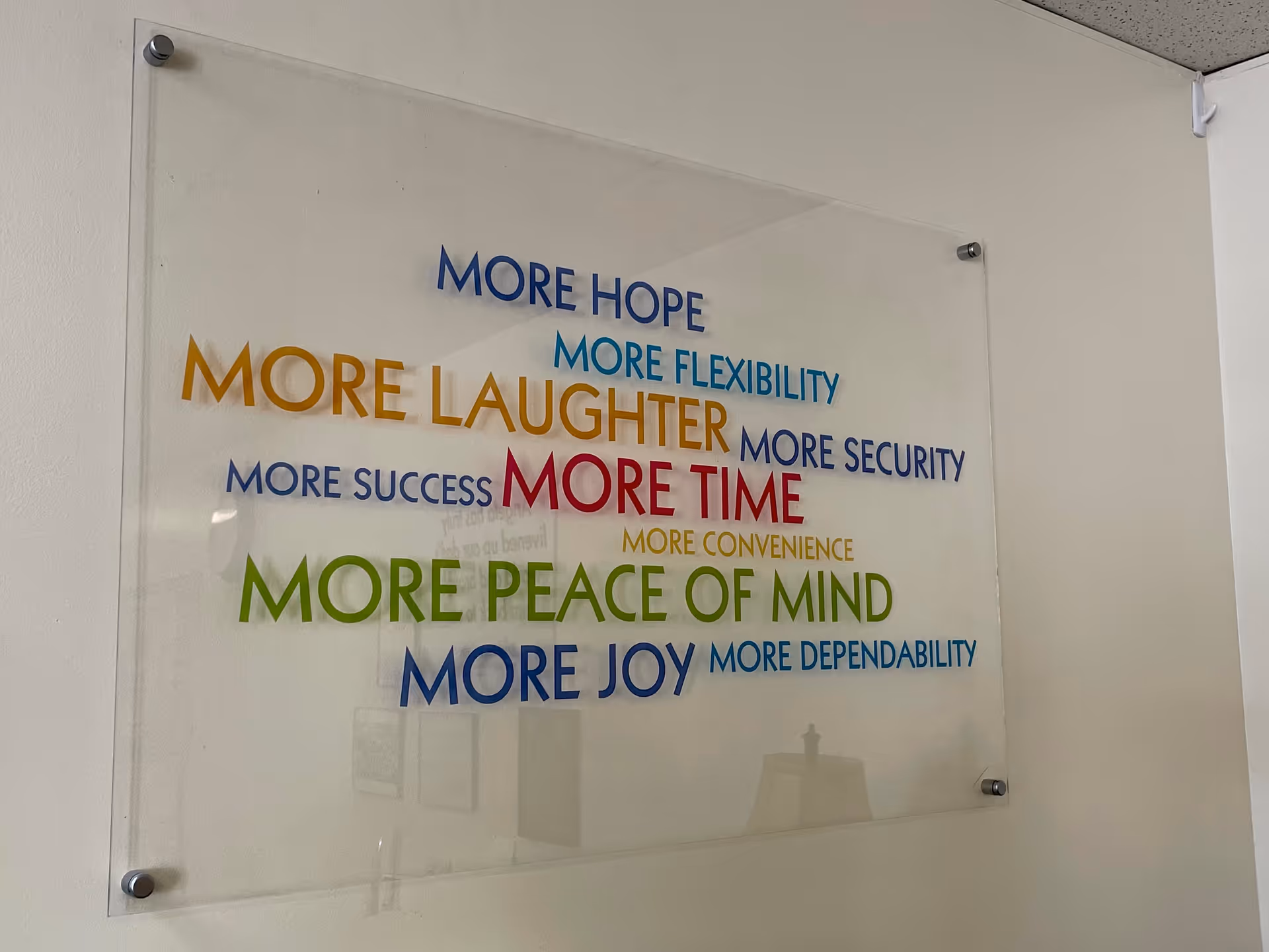 Interior wall with a large glass-framed sign featuring colorful motivational phrases.