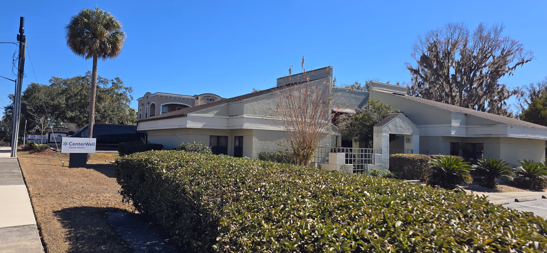 Exterior view of CenterWell Home Health facility with a low-rise building, hedges, and a sign.