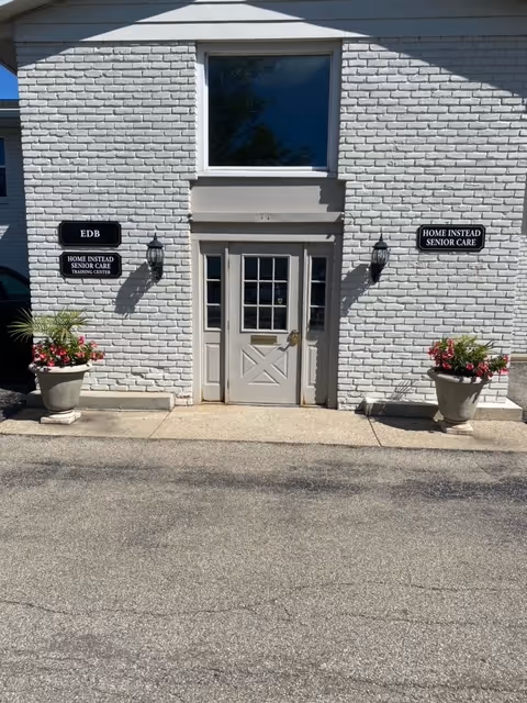 Exterior view of the Home Instead Senior Care entrance, brick building with two potted plants.