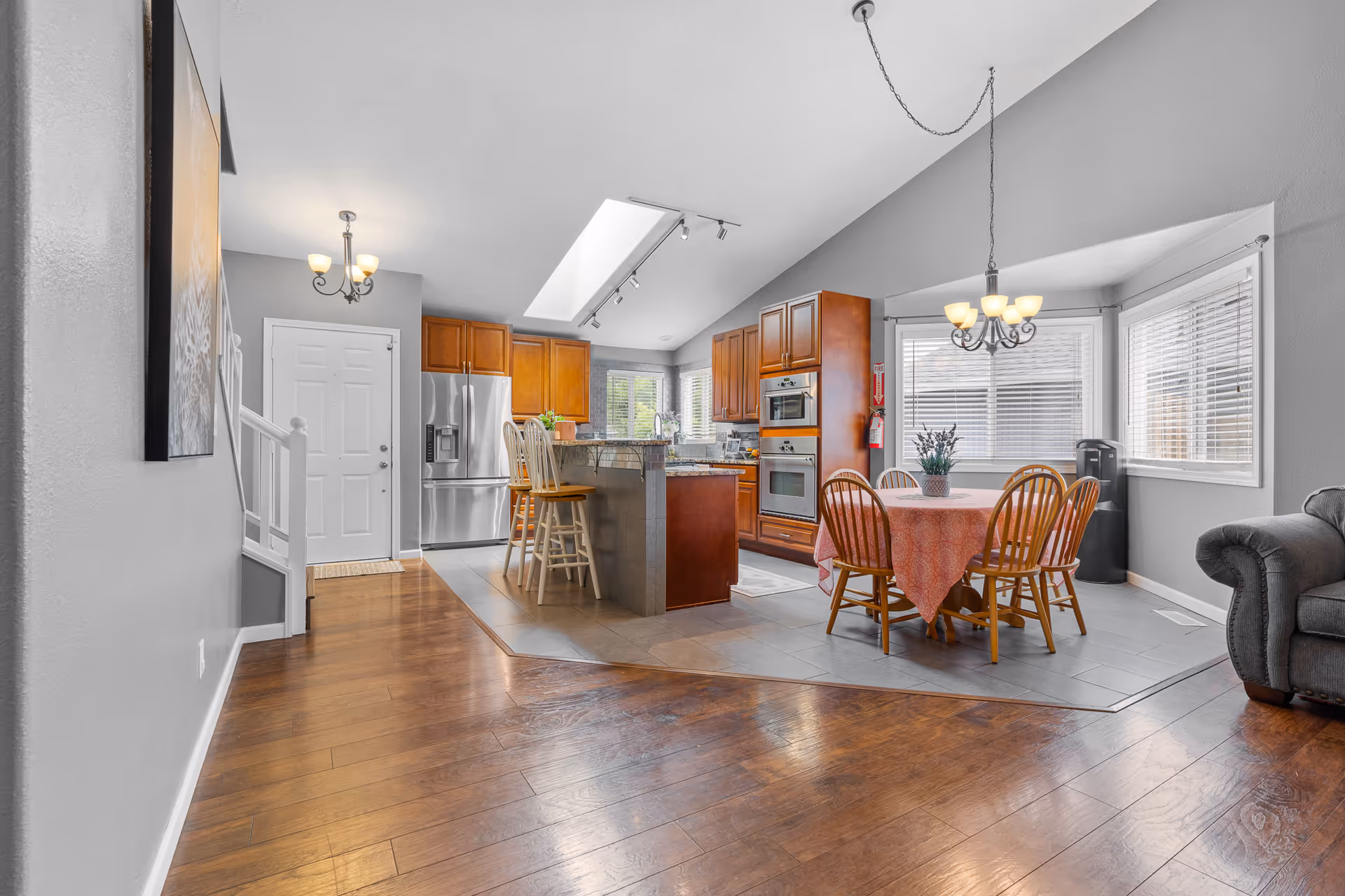 Bright open-plan kitchen and dining area featuring stainless appliances, wooden cabinetry, and a round table.