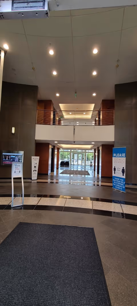 Bright lobby of a modern senior living facility with a two-story atrium and signage.