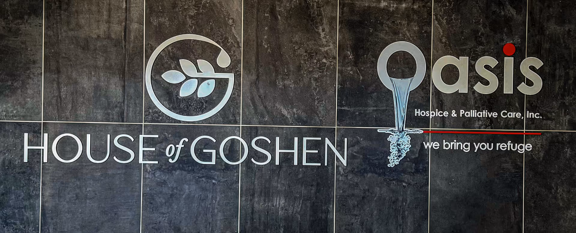 Interior wall with Oasis Hospice and House of Goshen branding logos.
