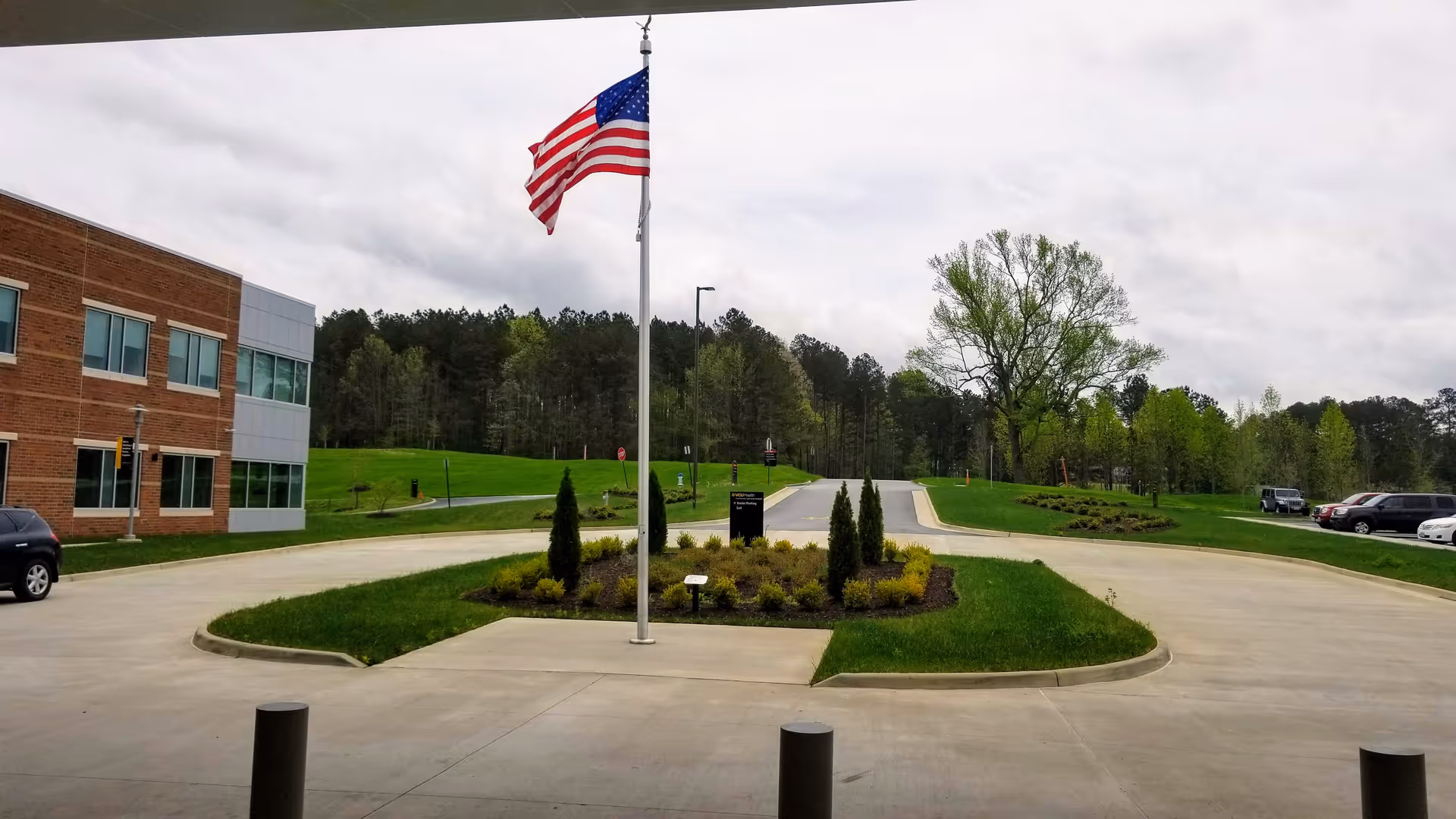 Exterior view of a hospital campus with flagpole, circular driveway, and landscaped island.
