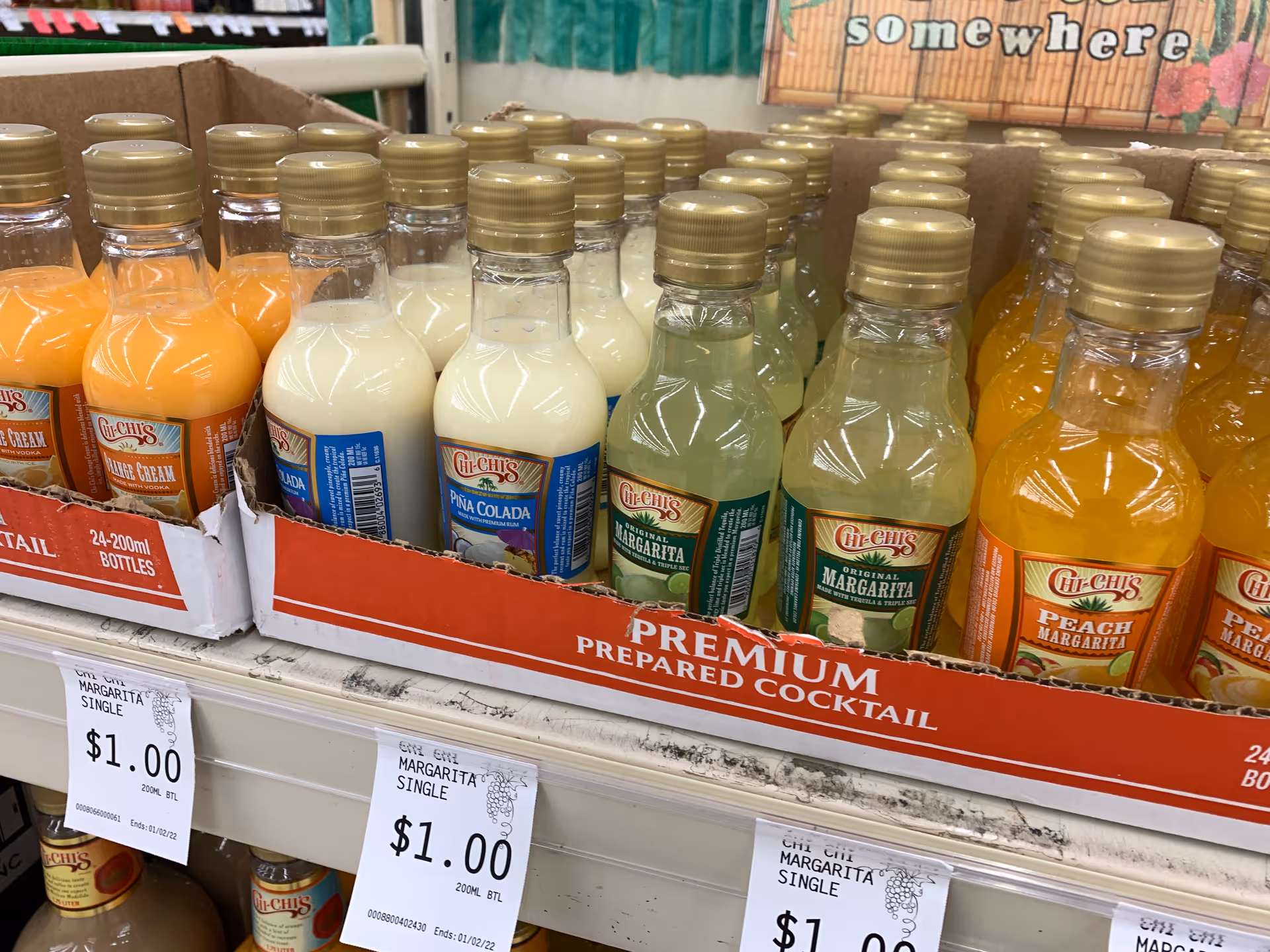 A shelf filled with bottled premade cocktails in a store display with colorful labels.