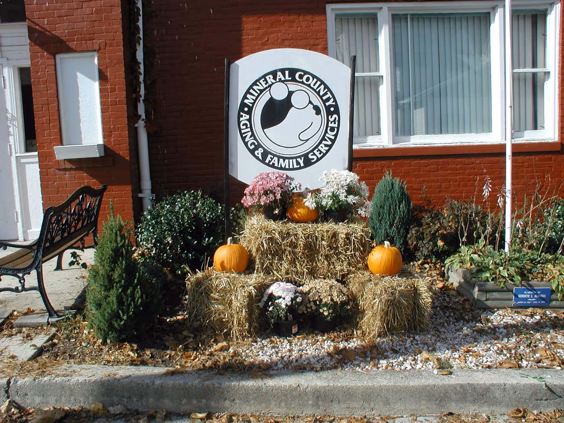 Outdoor autumn display with pumpkins and hay bales beside a sign for Aging & Family Services.