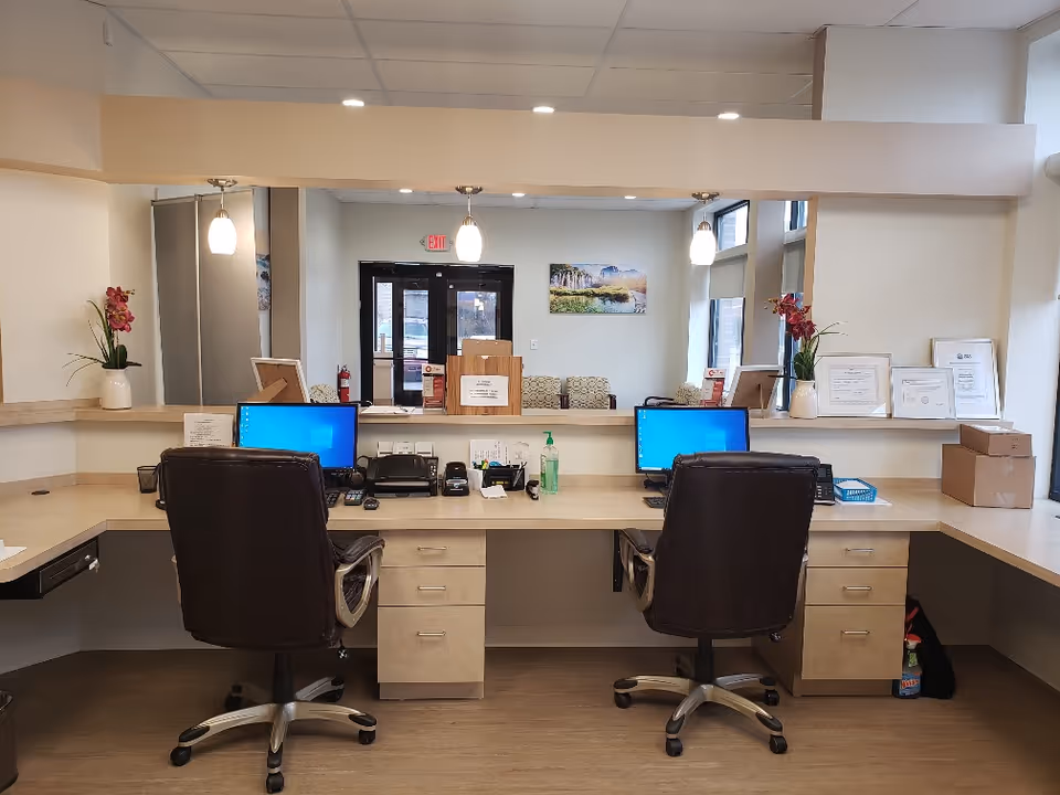 Reception desk with two computers and chairs in a modern facility lobby.
