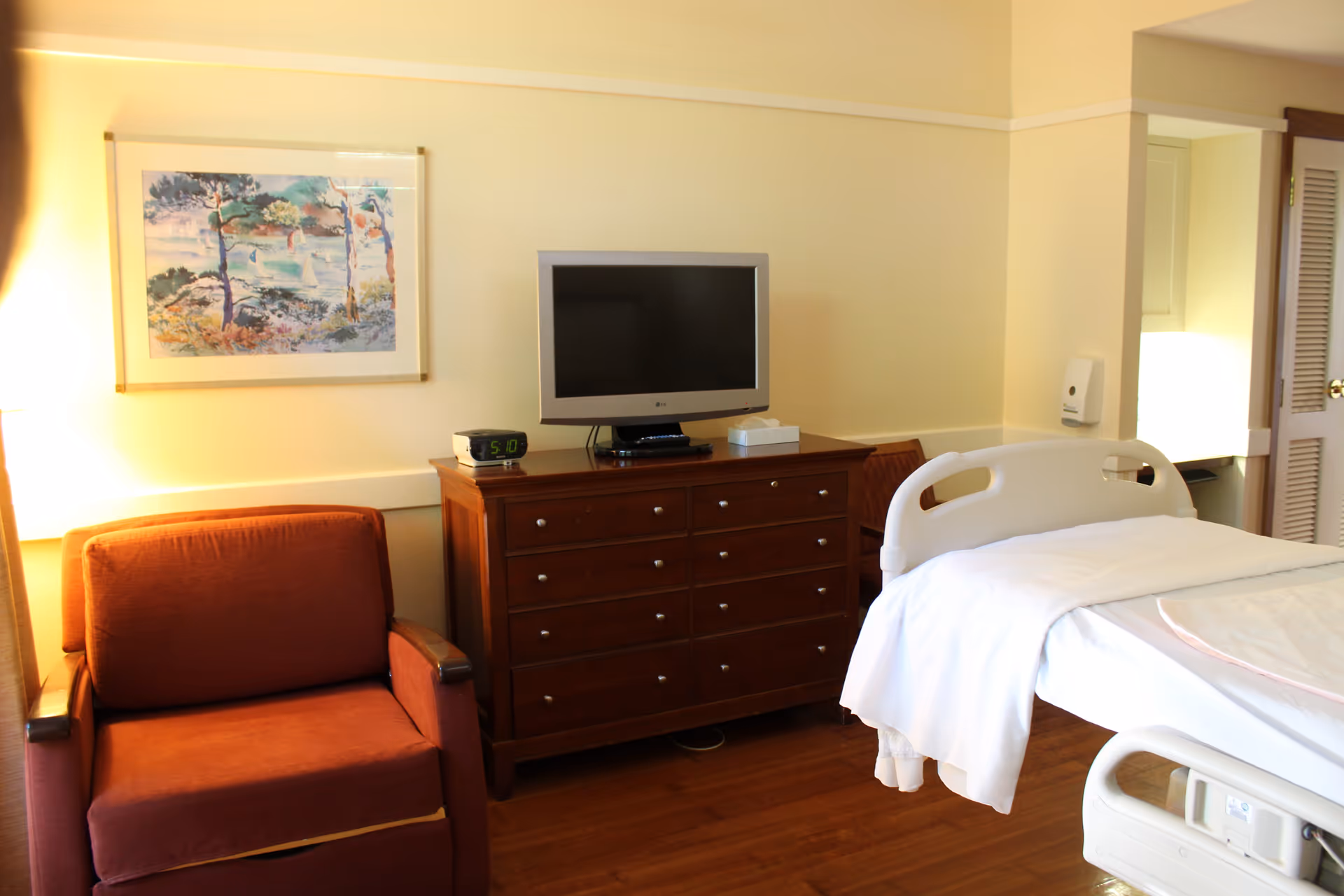 A patient room in Gilchrist Center Towson featuring a bed, dresser, chair, and TV.