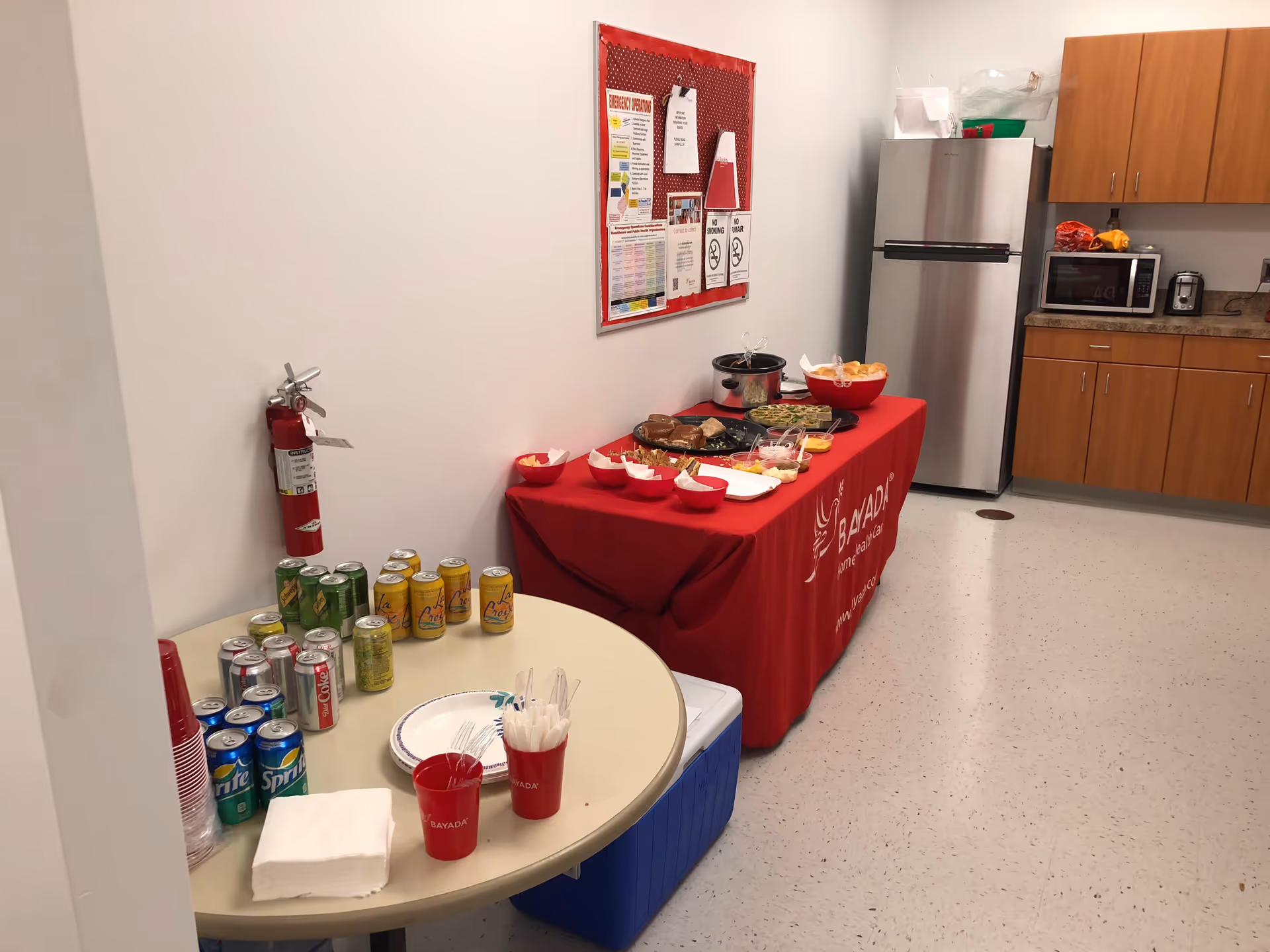 Interior kitchenette with a red snack table, beverages, and appliances in a BAYADA facility.