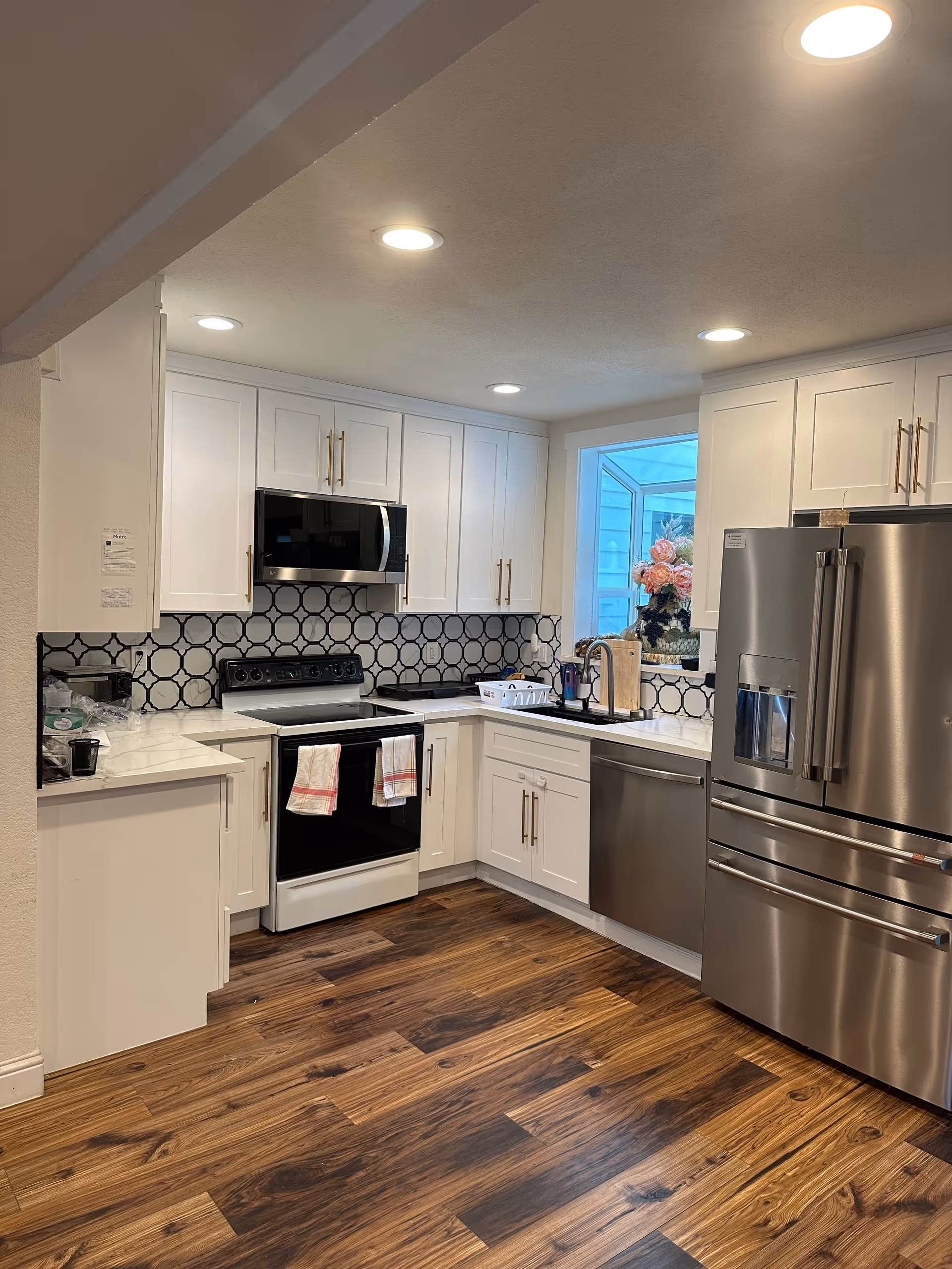 Bright white kitchen with cabinets, stainless steel appliances, and geometric backsplash.