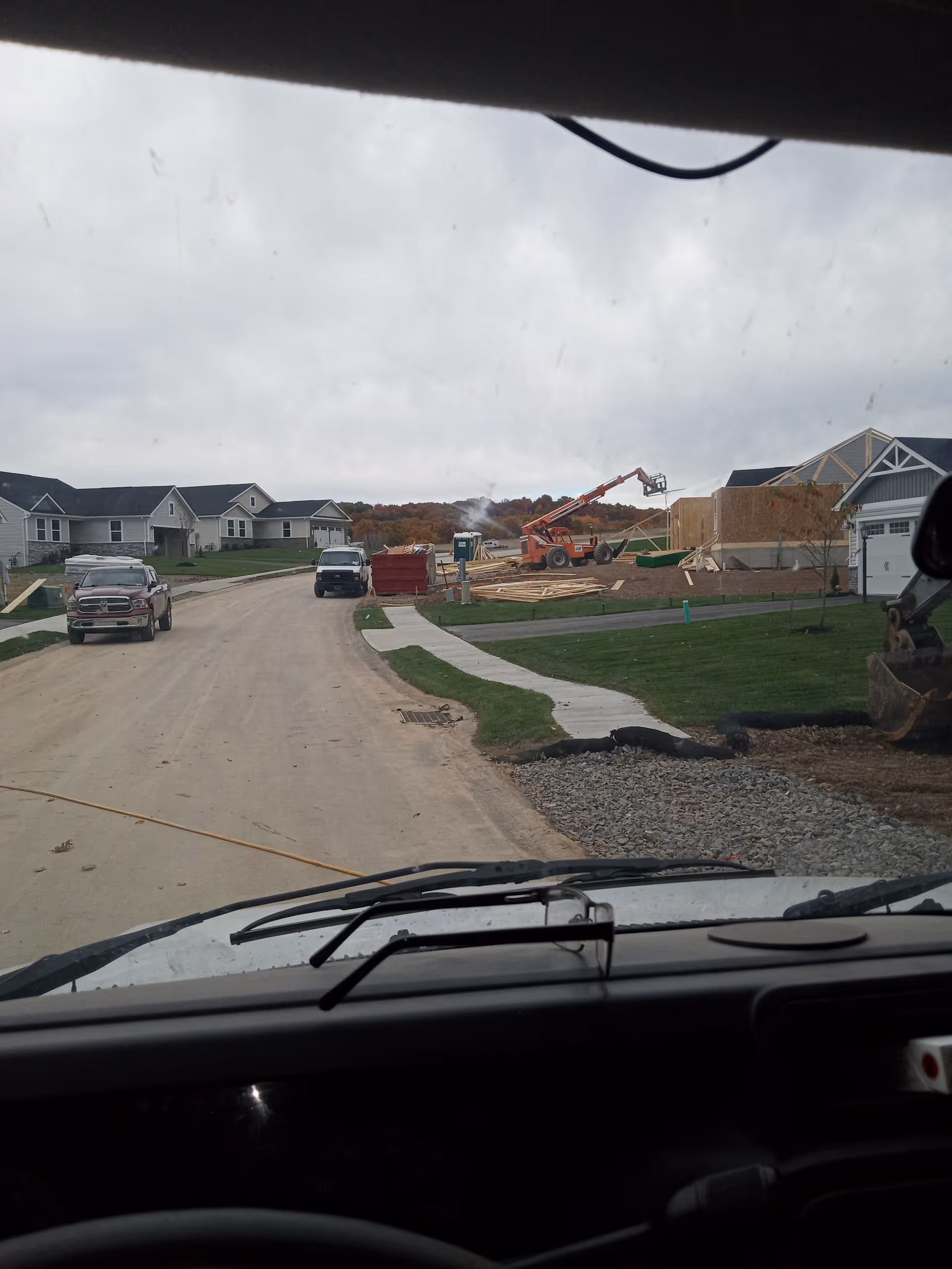Residential street under construction with wooden framing, equipment, and parked vehicles