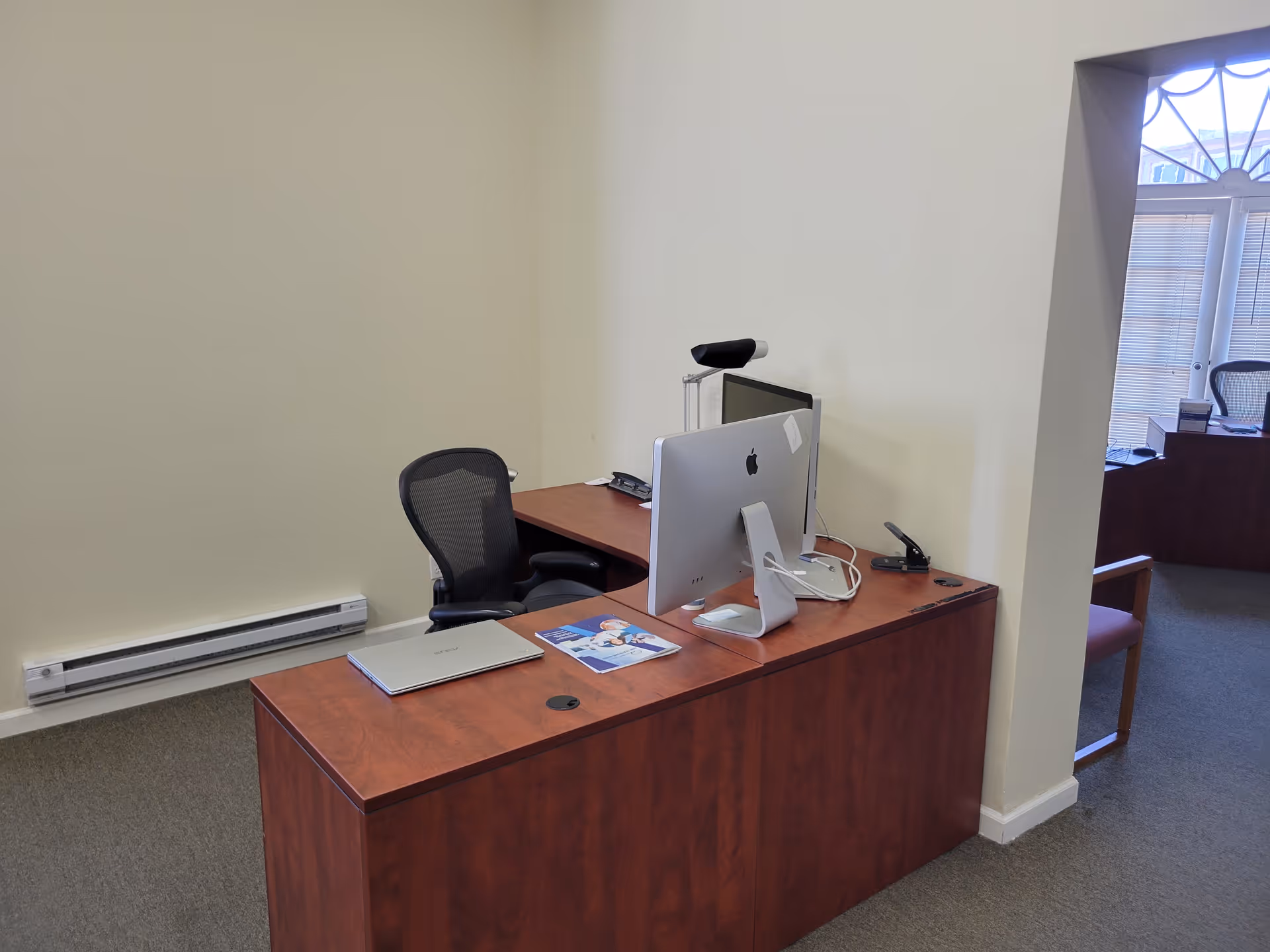 Interior office with a wooden desk, iMac computer, and office chair.
