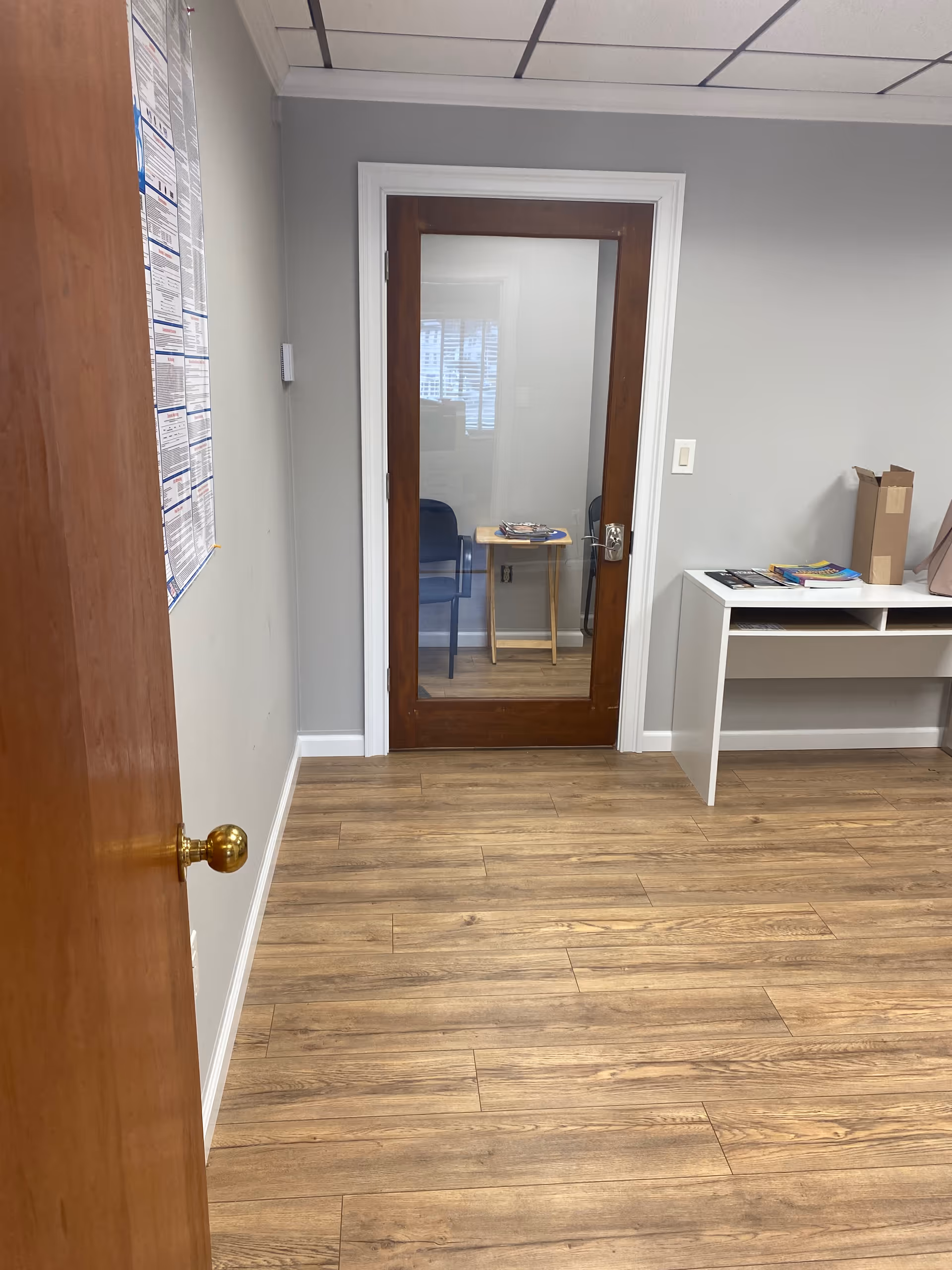 Hallway interior of a senior living facility with a glass-door room and a small table.