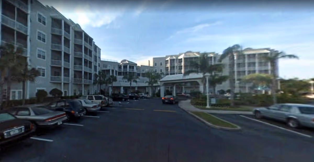 Exterior view of Senior Helpers senior living facility with parking lot and palm trees.