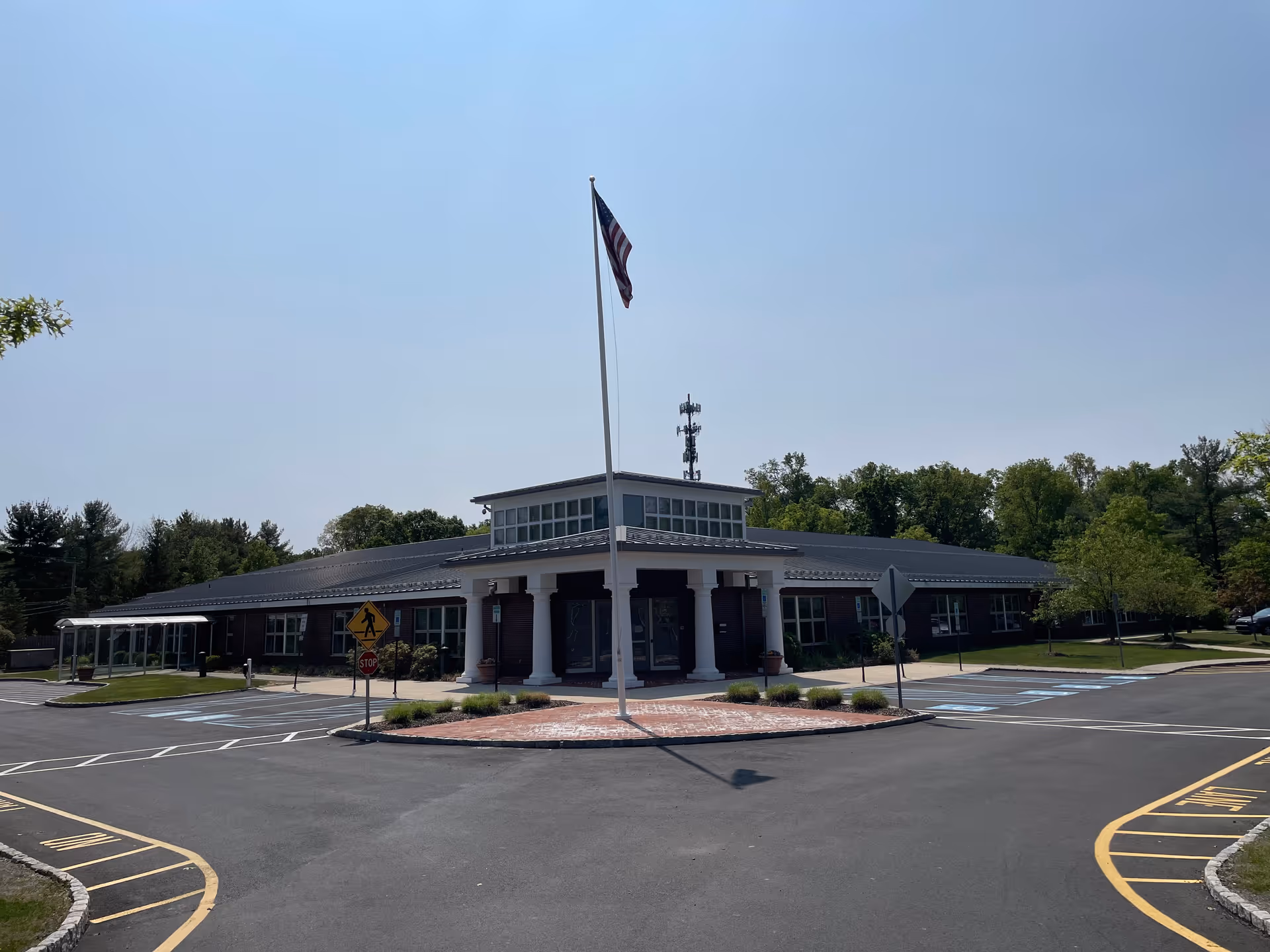 Exterior view of a single-story senior care building with a flagpole and entrance.