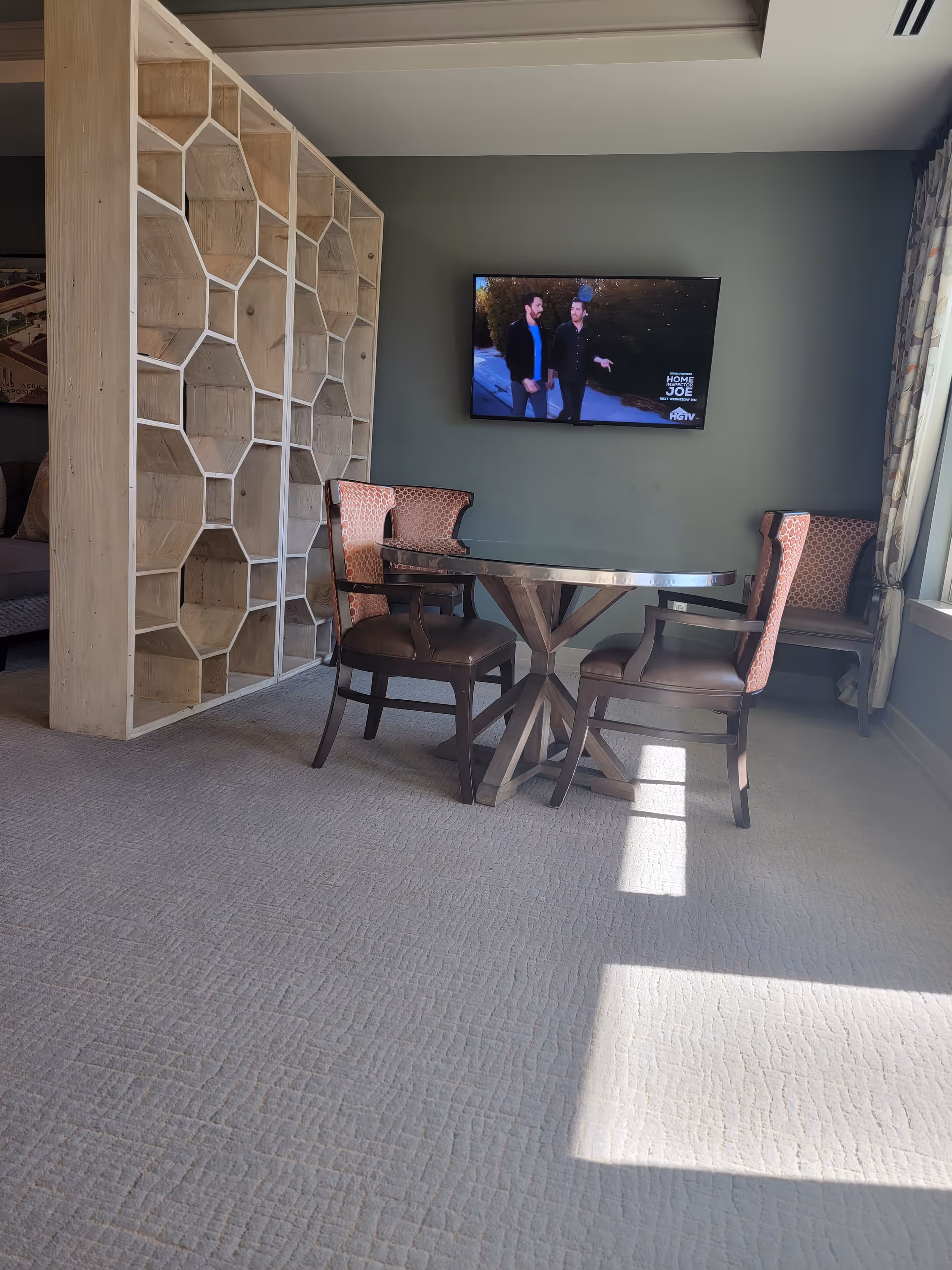 Living room area with table, chairs, shelves, and a wall-mounted TV.