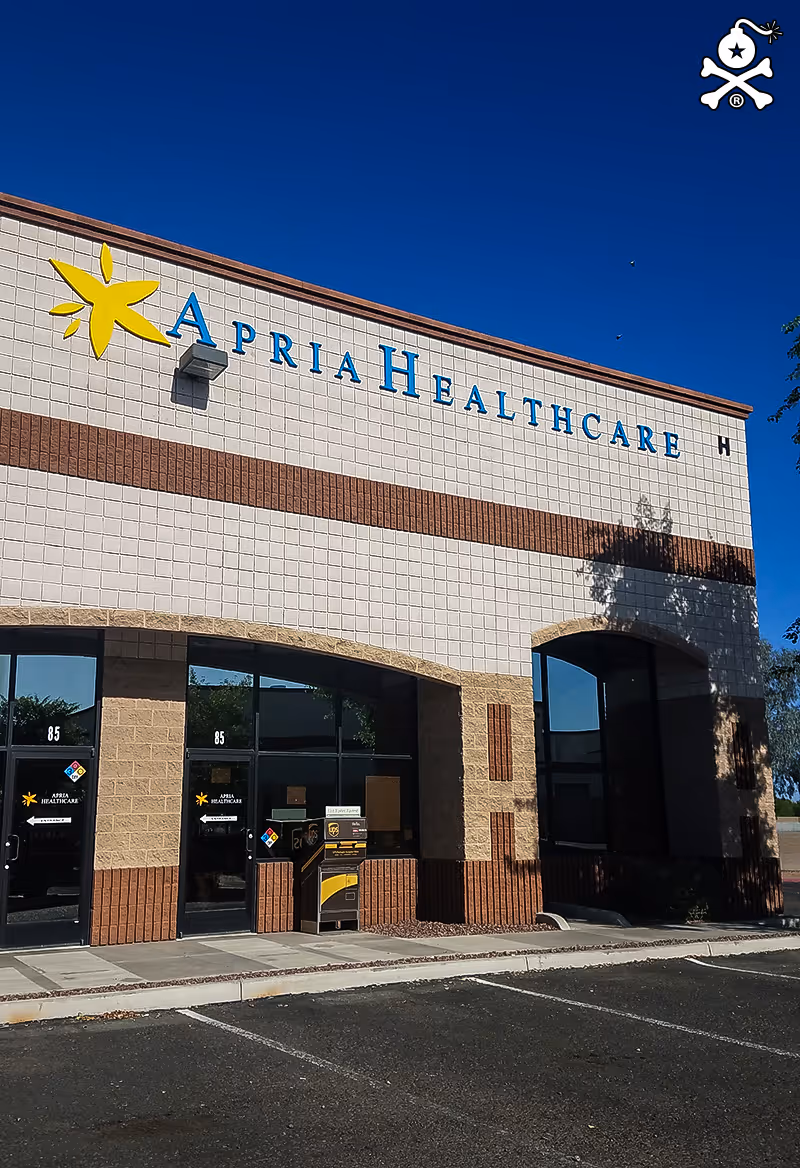 Exterior view of a facility building with Apria Healthcare signage and entrance doors.