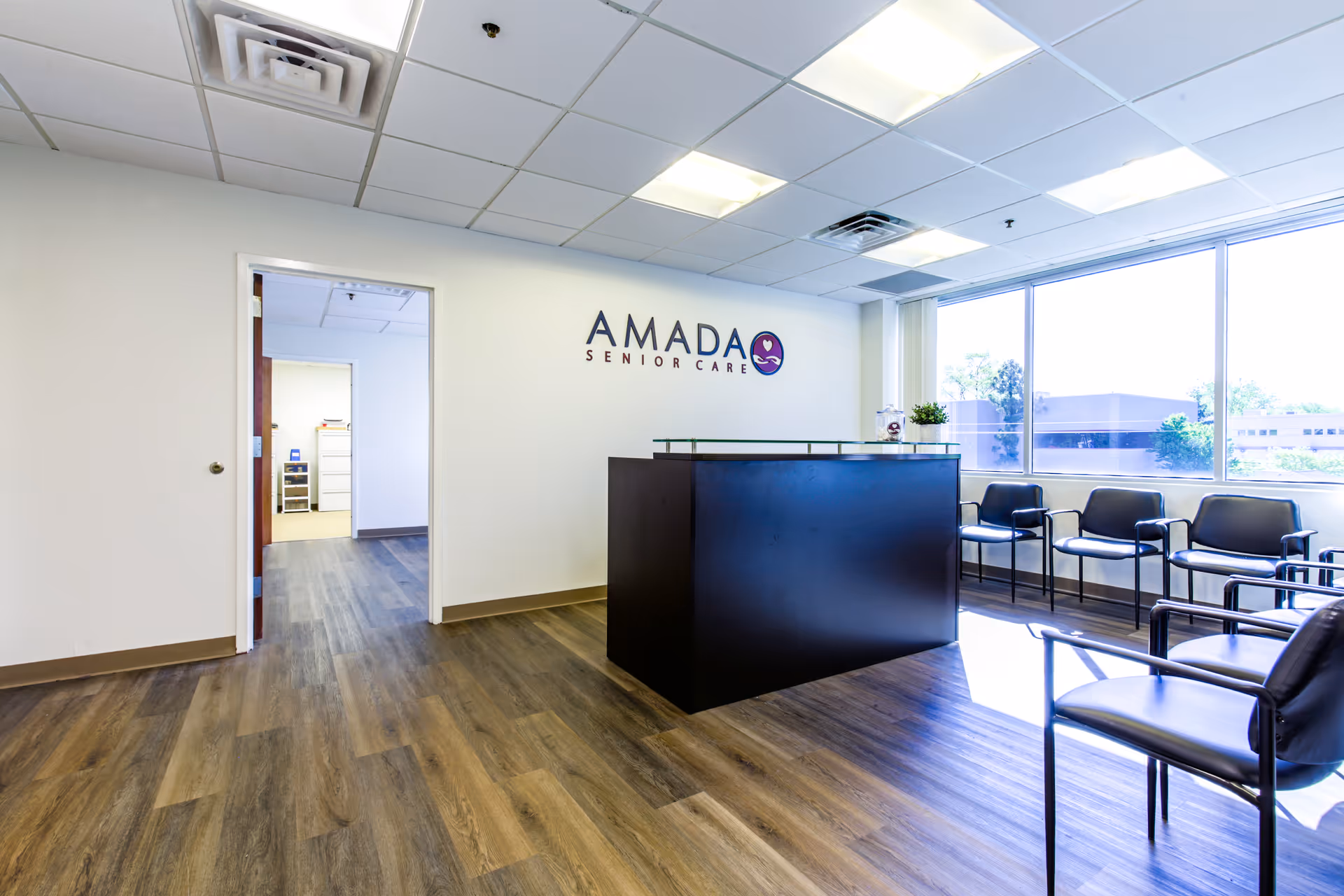 Reception area of Amada Senior Care with a black desk and waiting chairs.