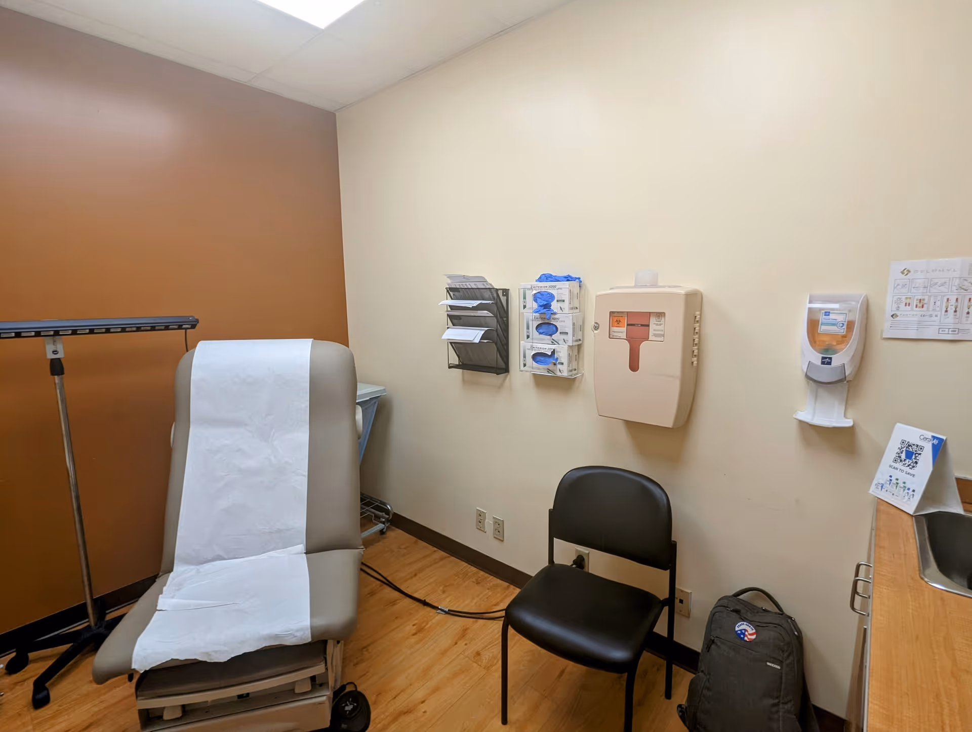 Exam room at Howard University Hospital with paper-covered chair and wall-mounted medical supplies.