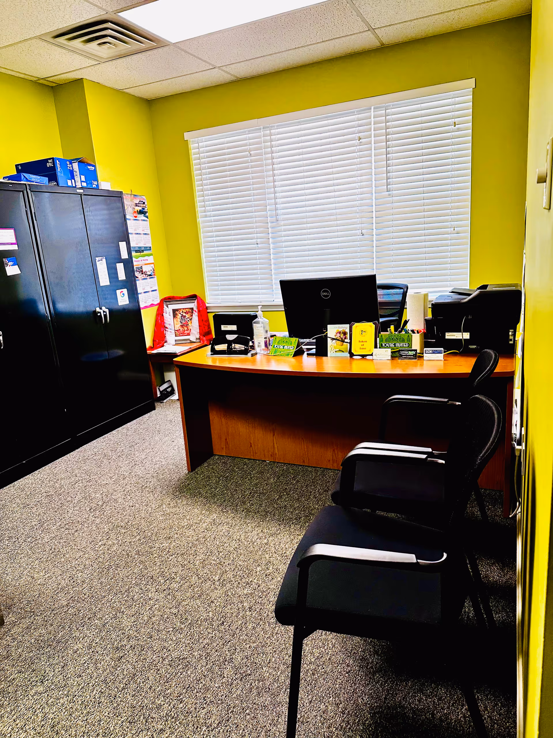 Office desk with computer and chairs against bright lime-green walls.