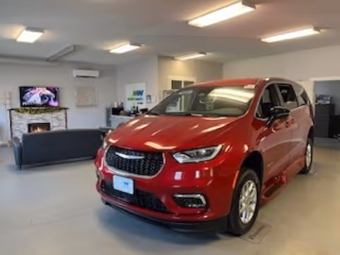Red SUV on display inside a showroom with seating and reception area.