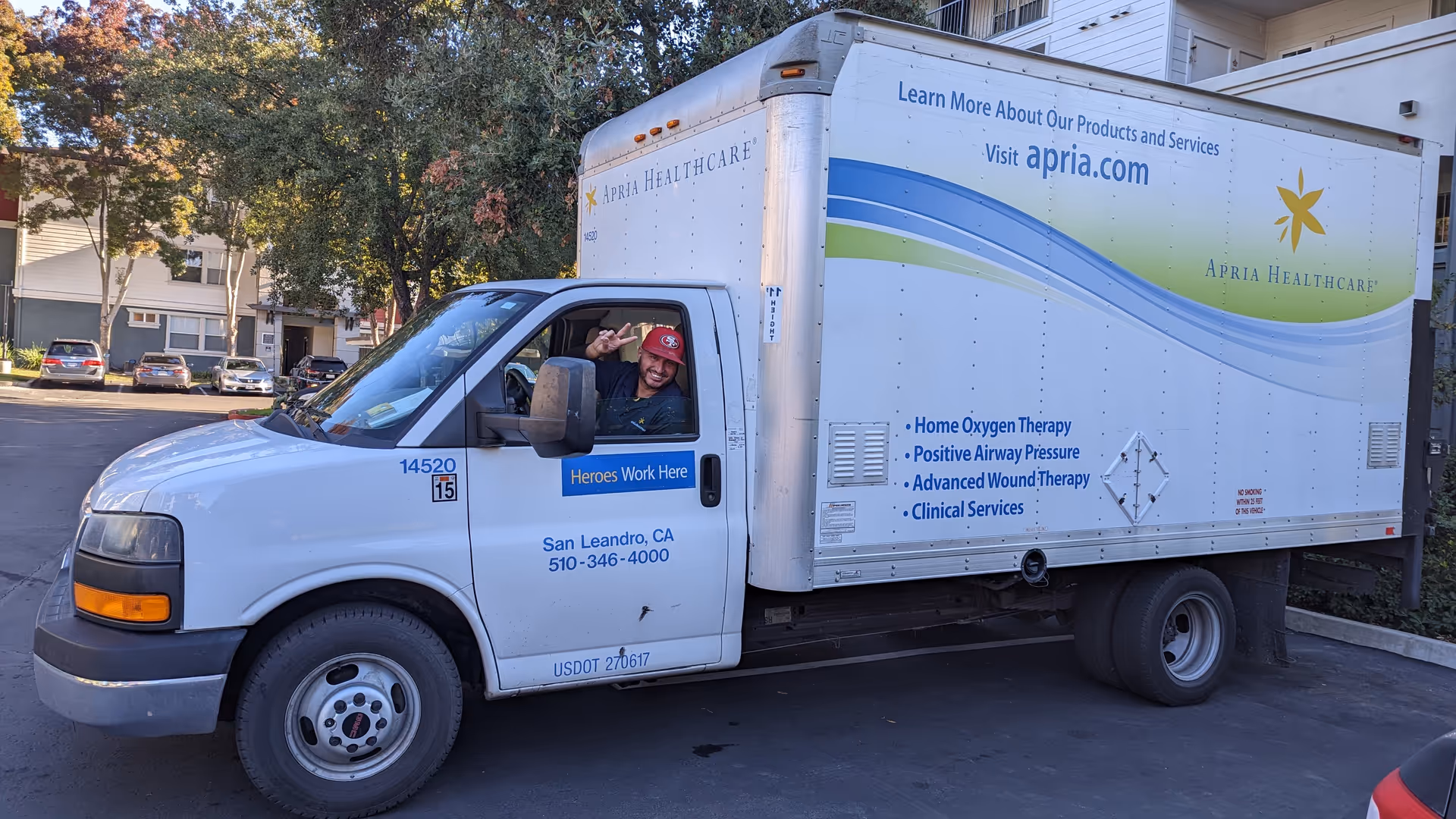 White Apria Healthcare delivery truck parked in a lot with a smiling driver.