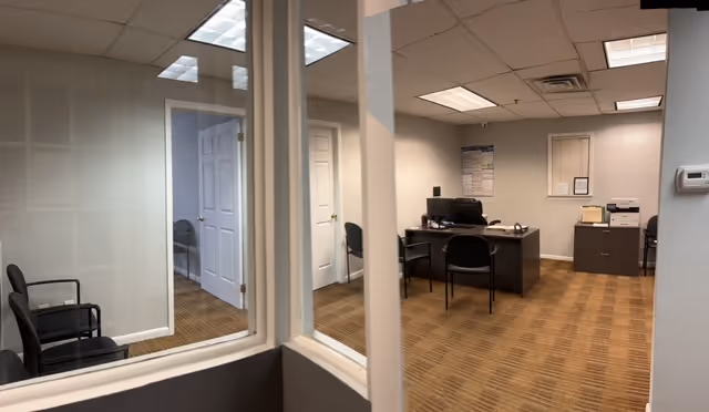 Interior office area with desks, chairs, and glass walls.