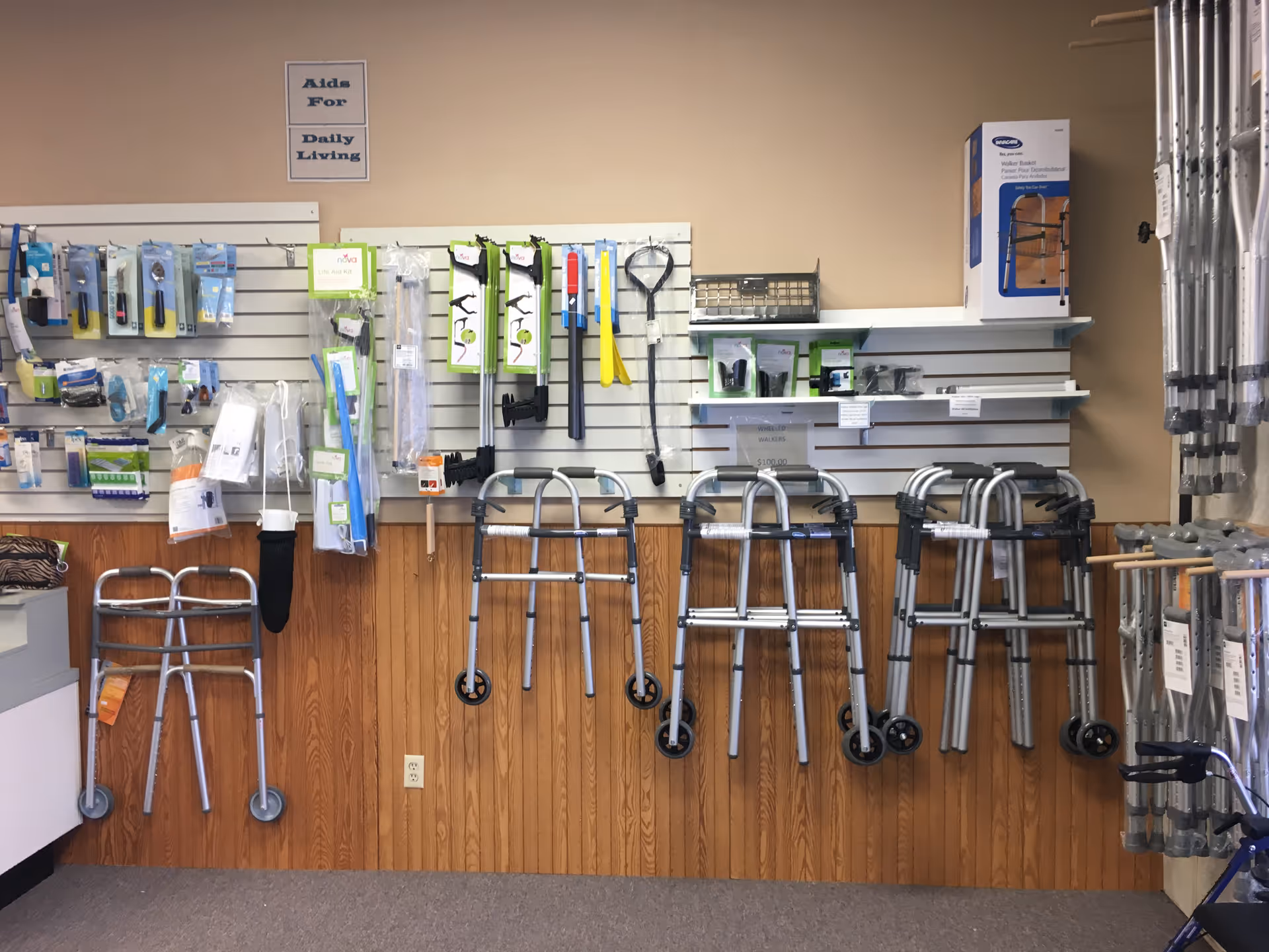 Row of walkers, crutches and mobility aids displayed on a wall in a retail medical shop.