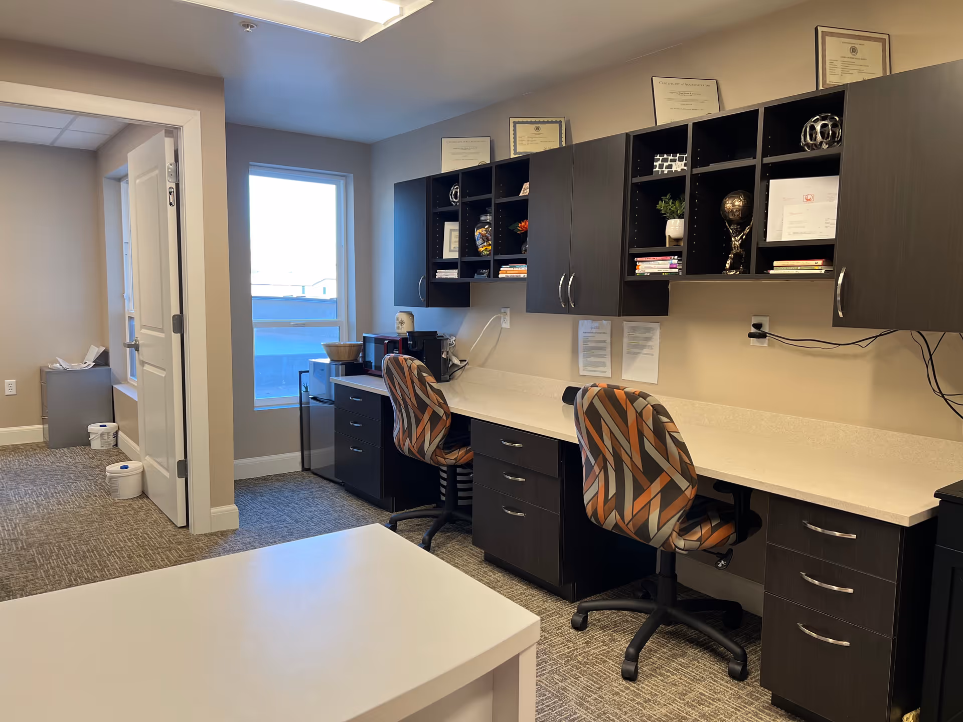Interior office area in Atlas Homecare and Hospice, with dark cabinetry and patterned chairs.
