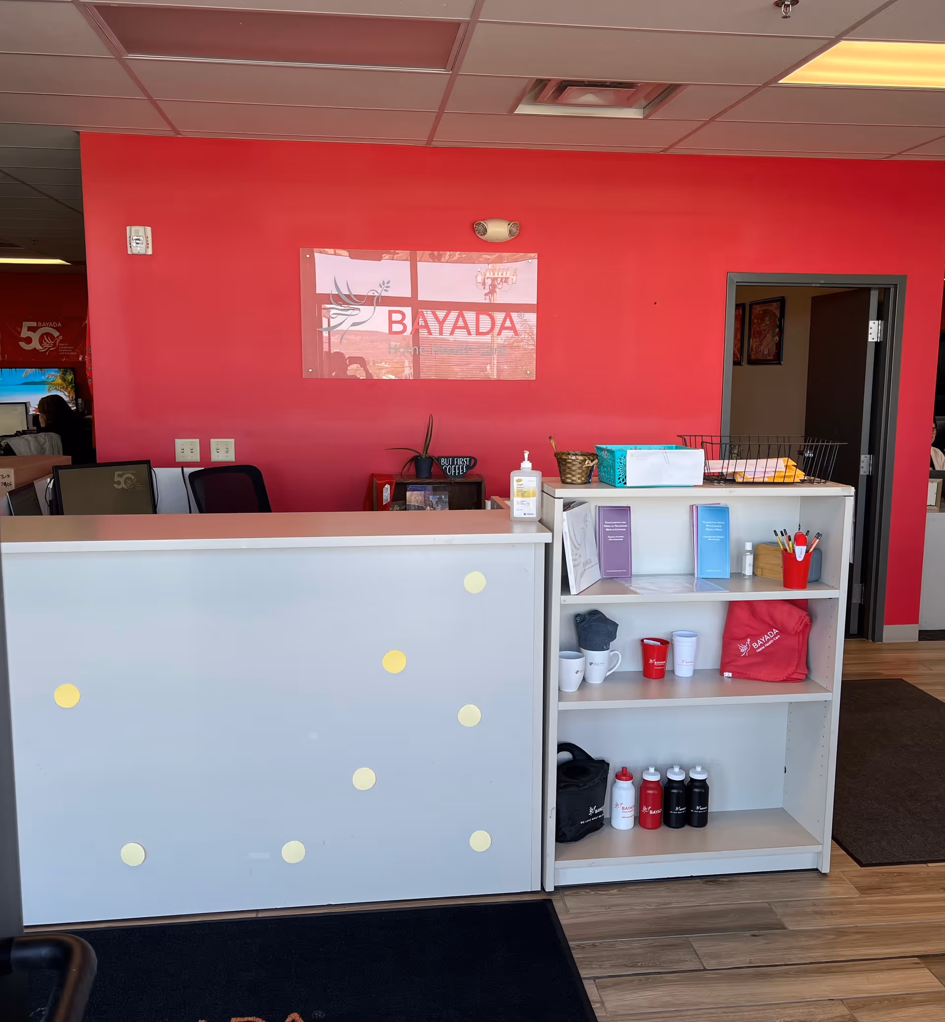 Bright pink reception area with BAYADA sign, front desk, and organized shelving.
