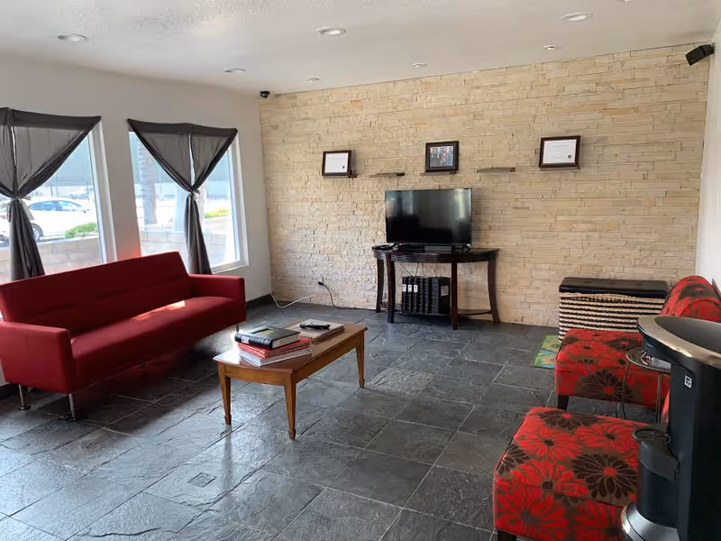 Cozy living room lounge with red sofa, coffee table, and a TV on a stone wall