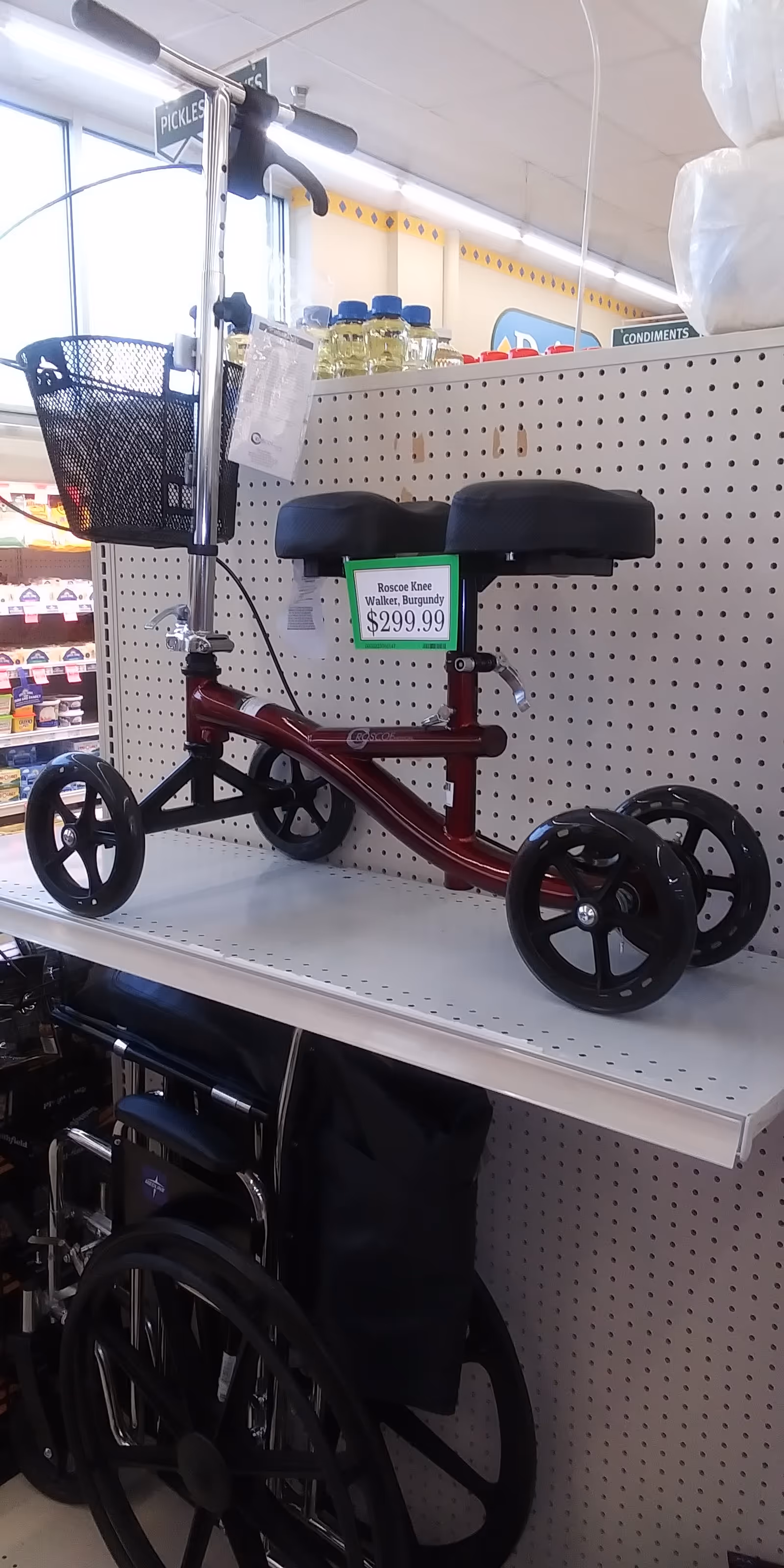 Red knee walker with front basket on a pegboard shelf inside a store