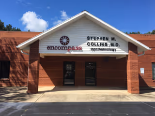 Brick storefront with a white gabled entrance and an optometrist sign.