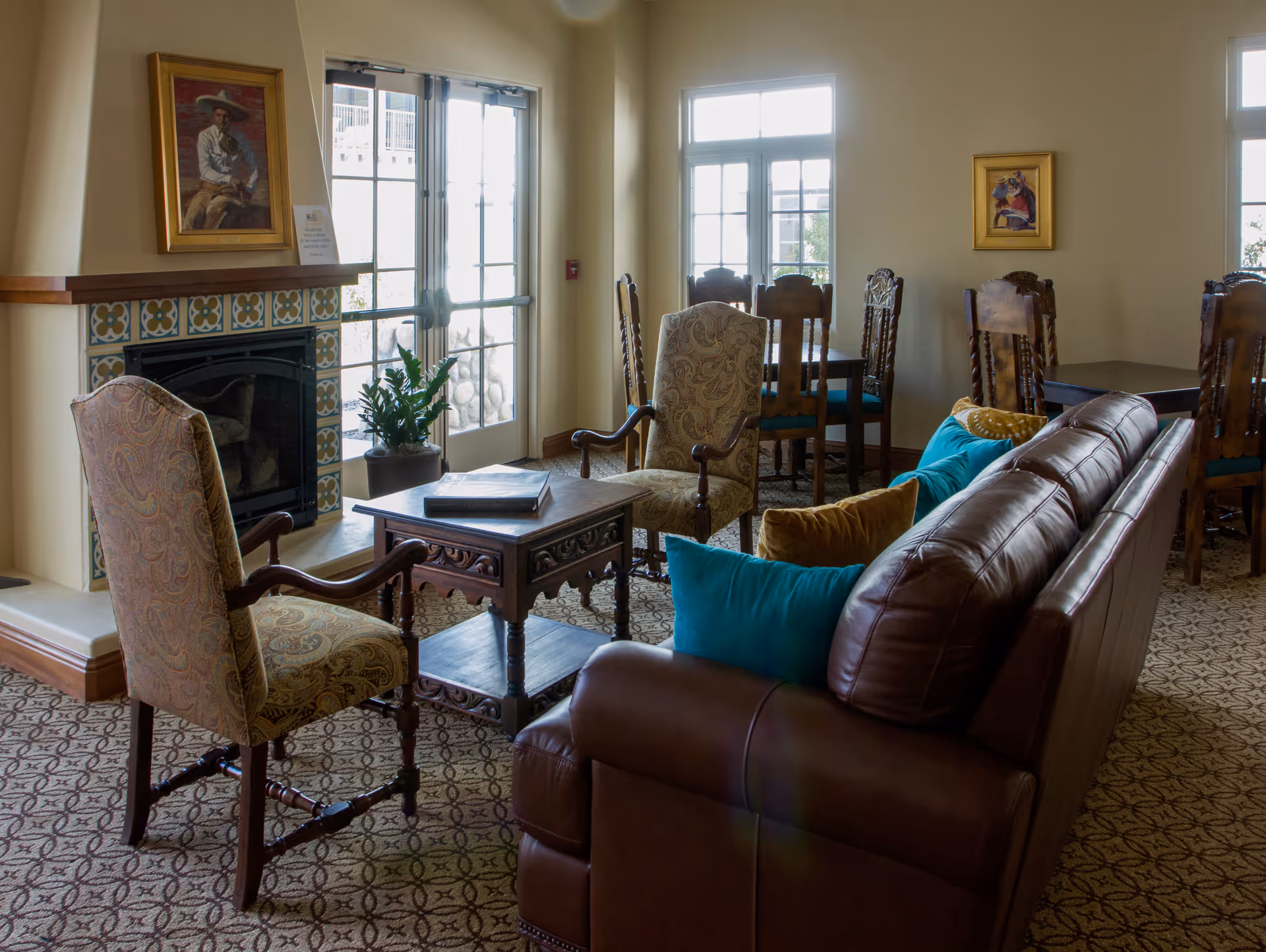 Comfortable living room with leather sofa, armchairs, fireplace, and dining area.