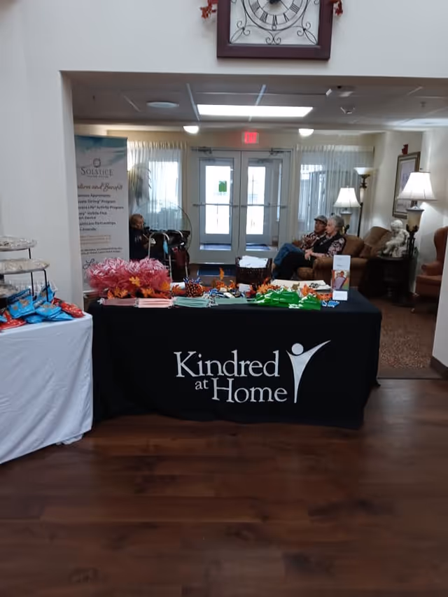 Lobby area with a Kindred at Home information table and residents seated in the background.