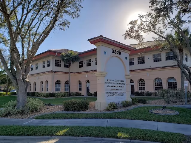 Two-story beige building with arched windows and a front entrance sign.