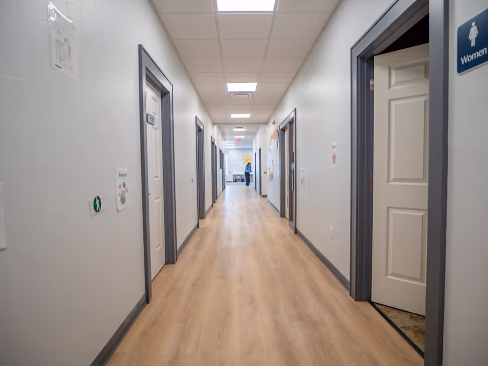 Bright interior hallway of a facility with closed doors along both sides.