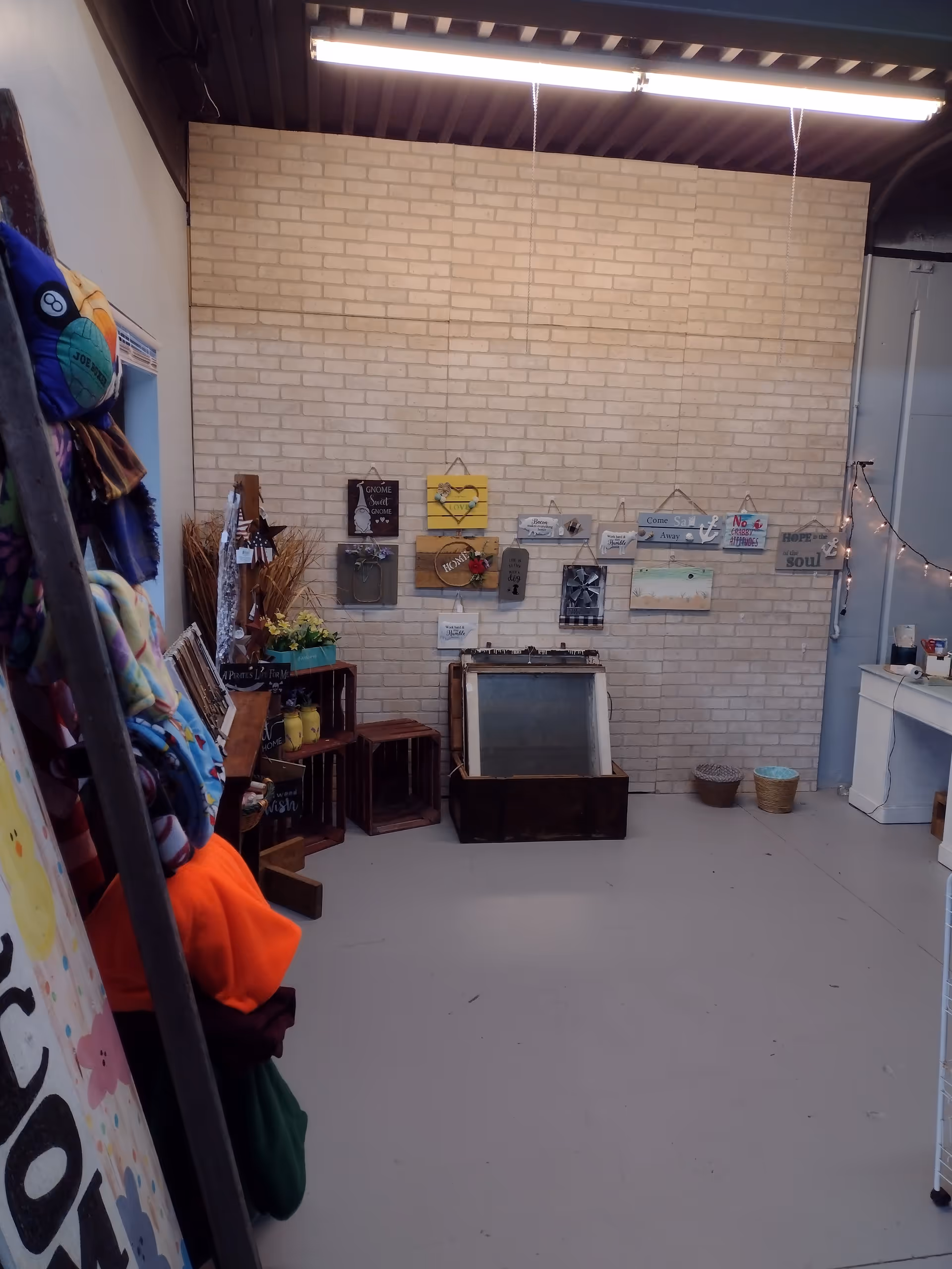 Indoor activity space with brick accent wall, hanging signs, crates, and display items.