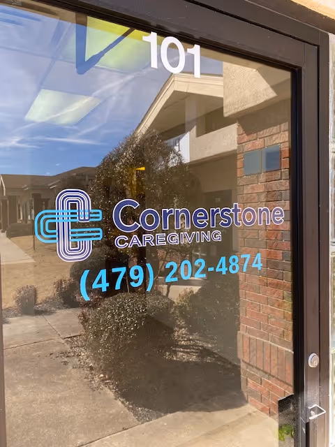 Glass door entrance displaying Cornerstone Caregiving logo, phone number, and the number 101.