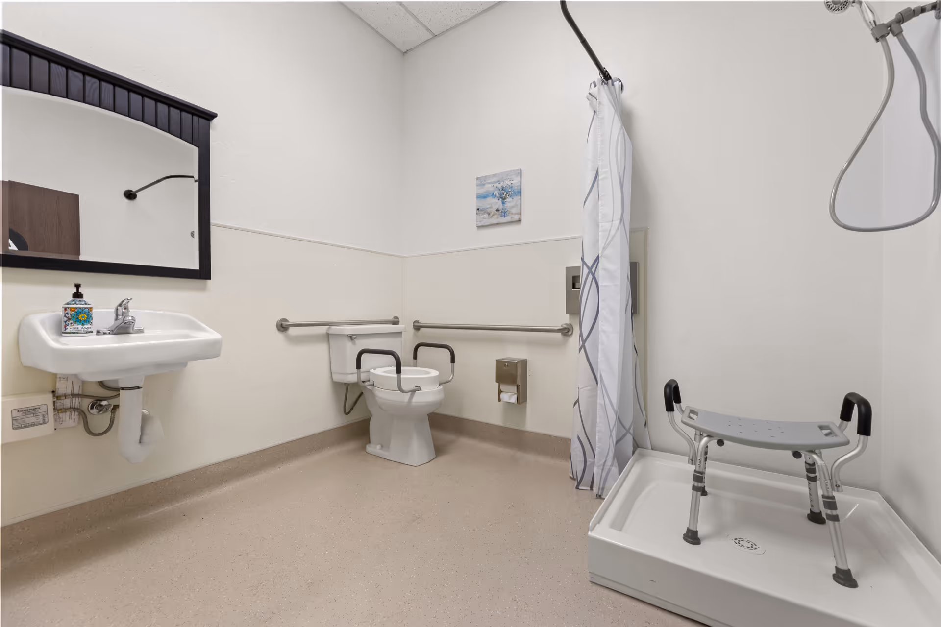 Accessible senior bathroom with grab bars, shower chair, curtain, sink, and toilet.