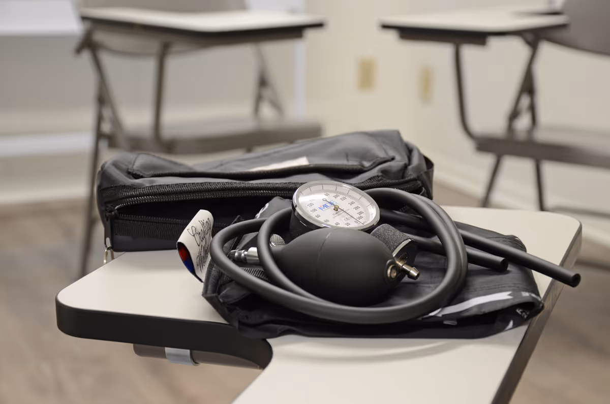 Stethoscope and blood pressure cuff lie on a desk in a clinical exam room.