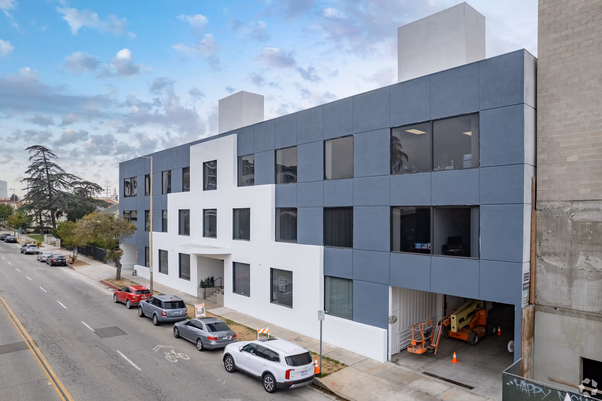 Modern multi-story building with blue-gray exterior panels on a city street; no people visible.