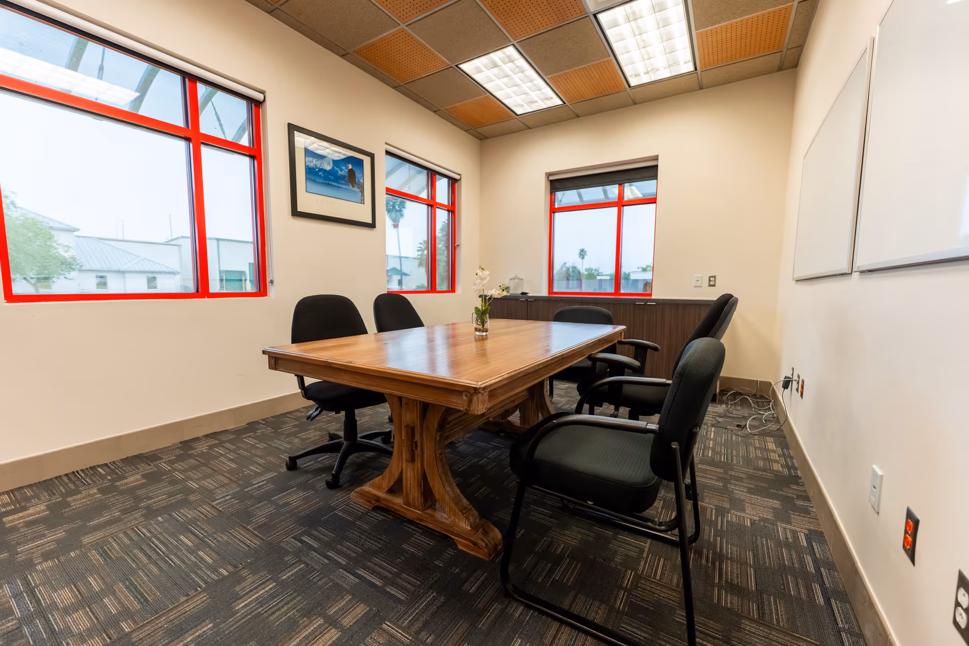 Wooden conference table with chairs in a bright, windowed meeting room.
