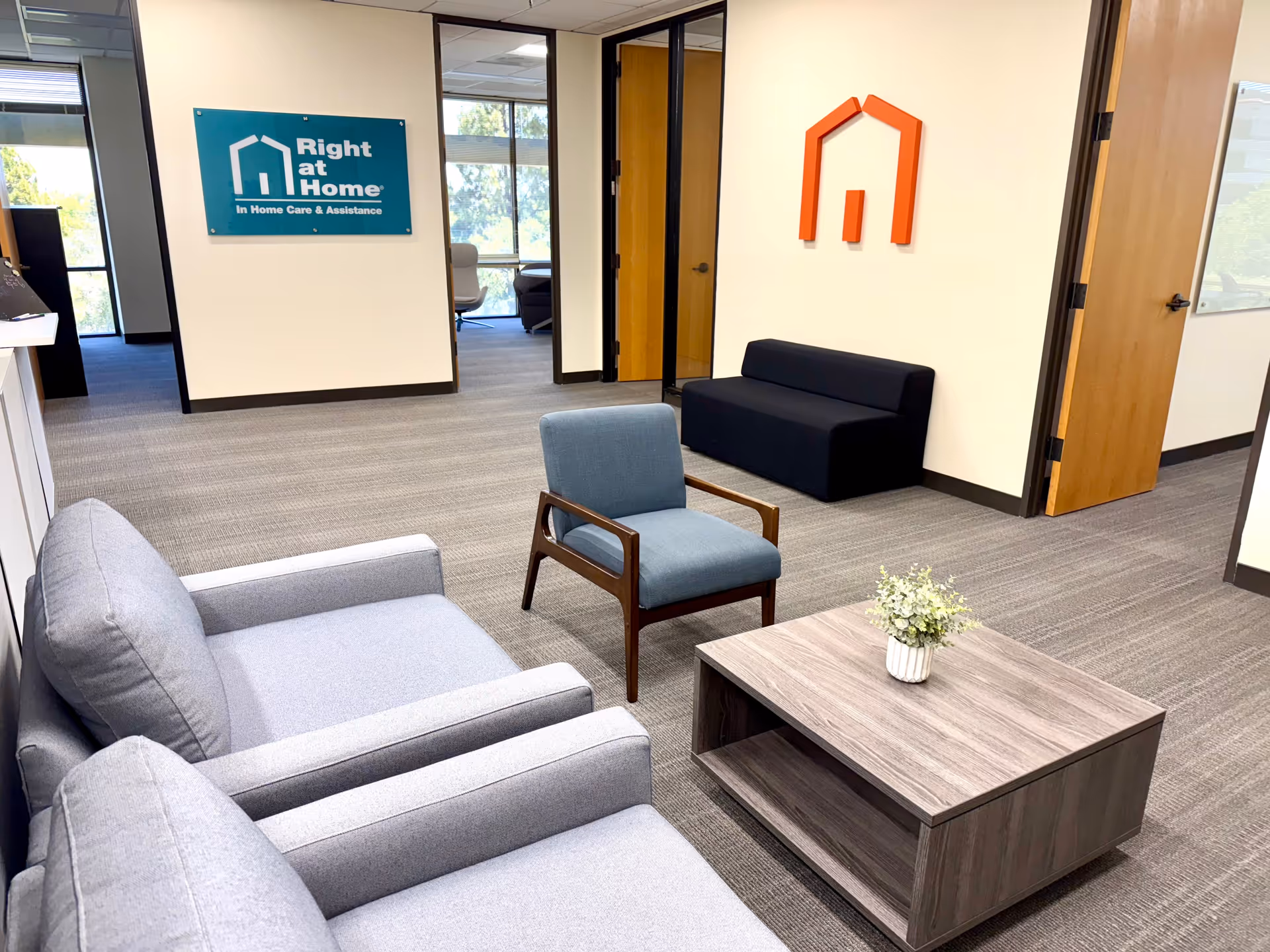 Modern facility lobby with sofas, chairs, coffee table, and Right at Home signage.