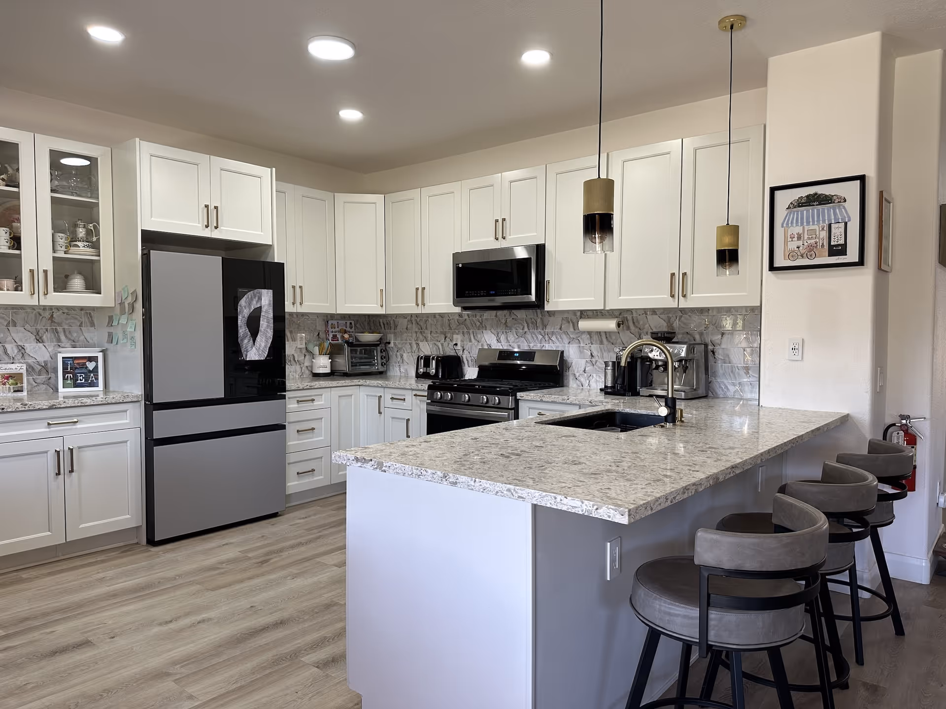 Bright, modern kitchen with white cabinets, stainless appliances, and a granite island.