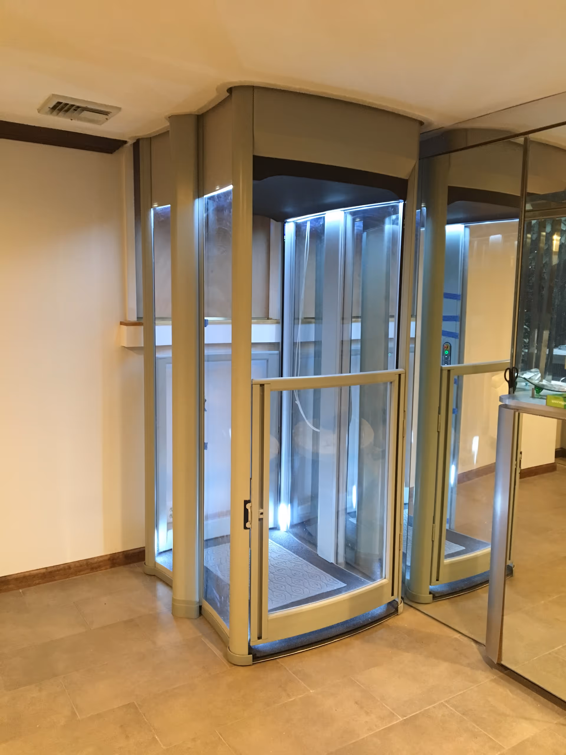 Interior lobby area featuring a glass revolving door with metallic frame and blue accent lighting.