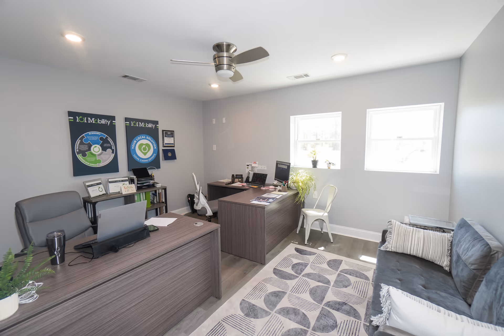 Modern office reception area for 101 Mobility with desks, seating, posters, and two windows.