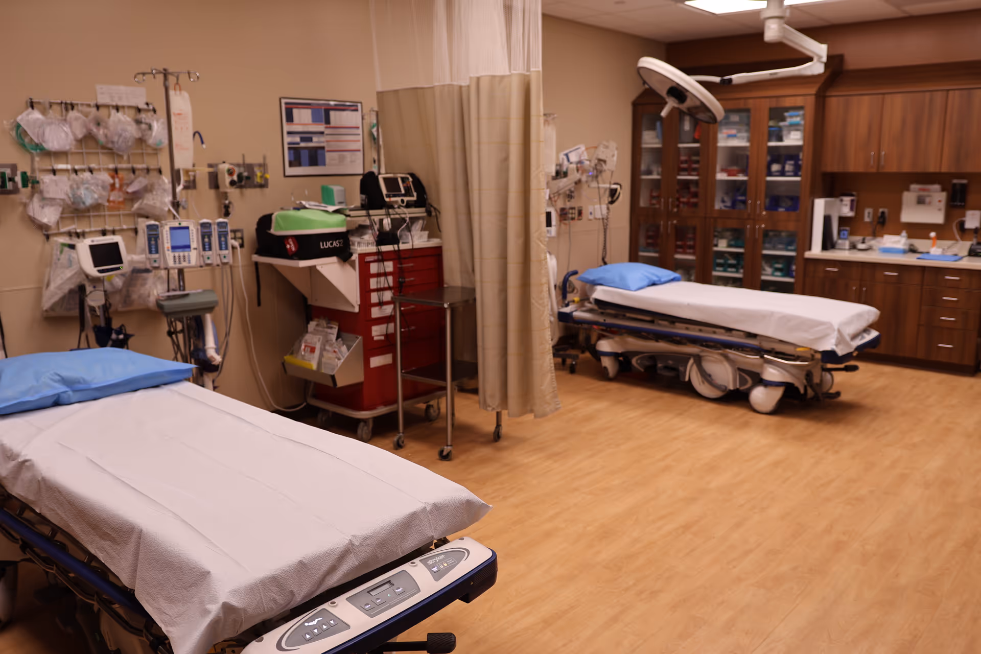 Hospital treatment room with two beds, curtains, and medical equipment.
